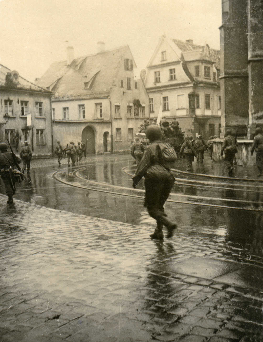 Das Schwarz-Weiß-Bild zeigt amerikanische Soldaten, die sich mit Fahrzeugen und zu Fuß am Dom vorbei Richtung Innenstadt bewegen 