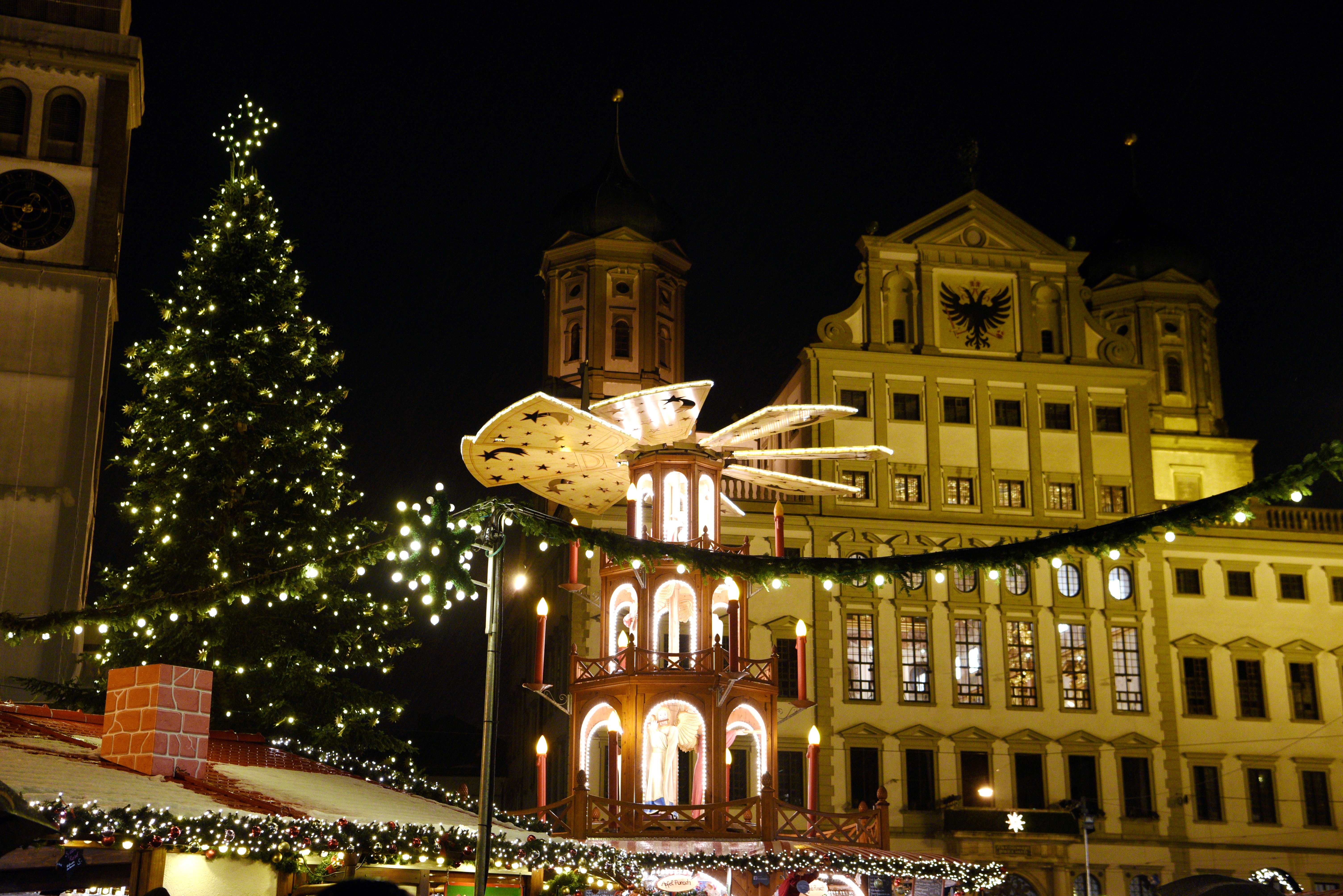 Die Pyramide und der Christbaum auf dem Christkindlesmarkt sind vor dem beleuchteten Rathaus und dem Perlachturm zu sehen.