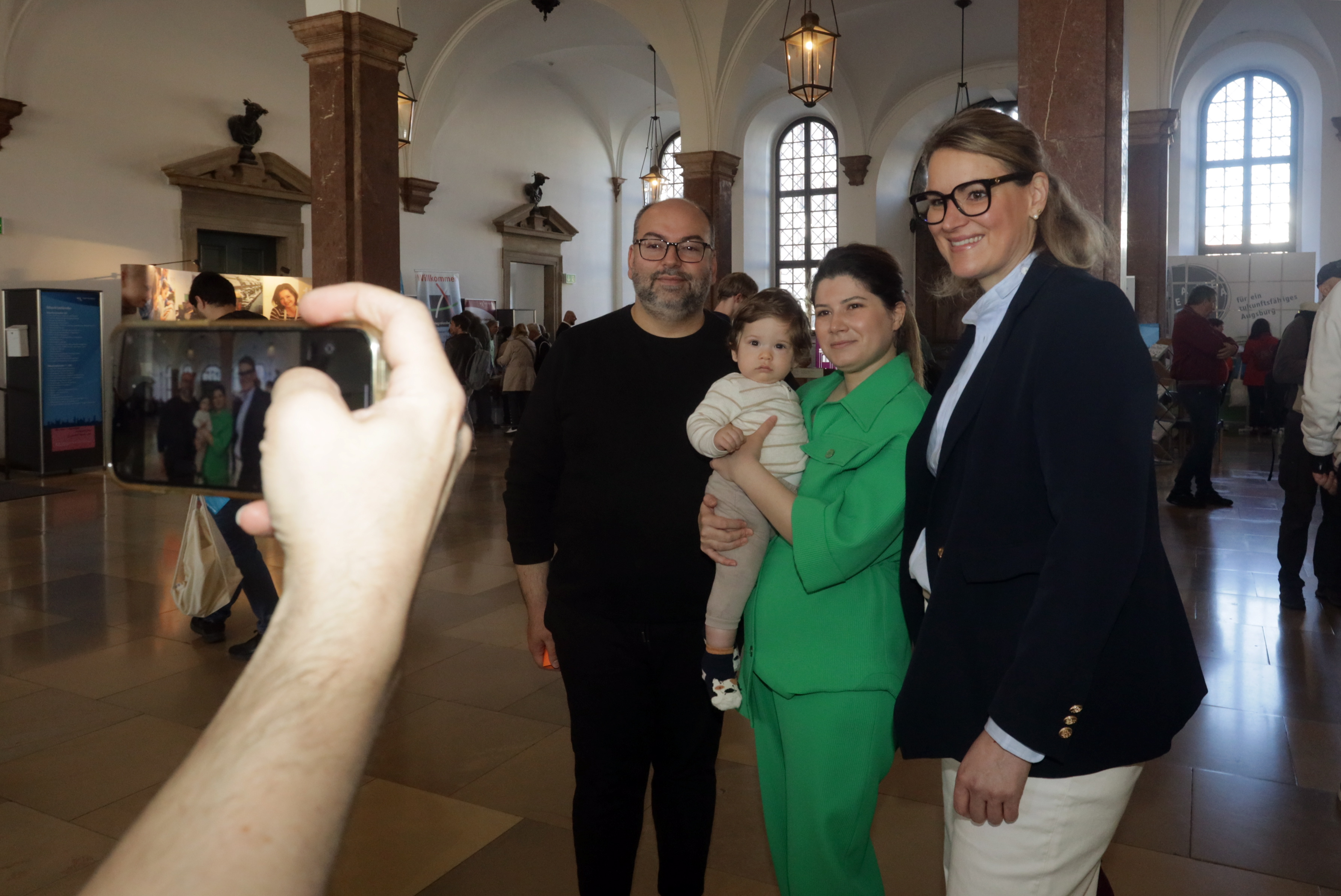 Eine junge Familie posiert mit Oberbürgermeisterin Eva Weber für ein Foto