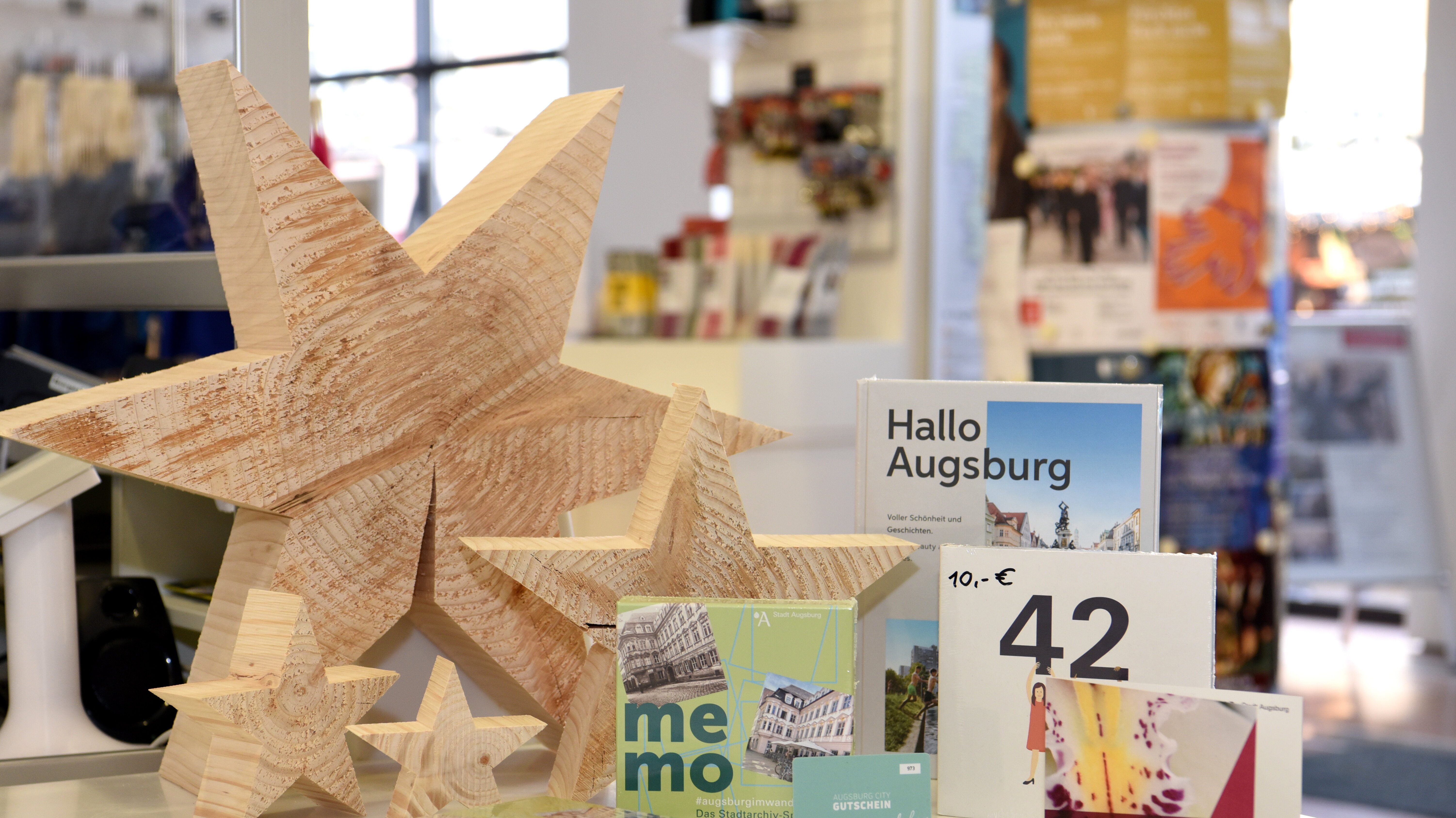 vier hölzerne Sterne, ein Buch, ein Geschenk und ein Memory-Spiel auf einer Theke