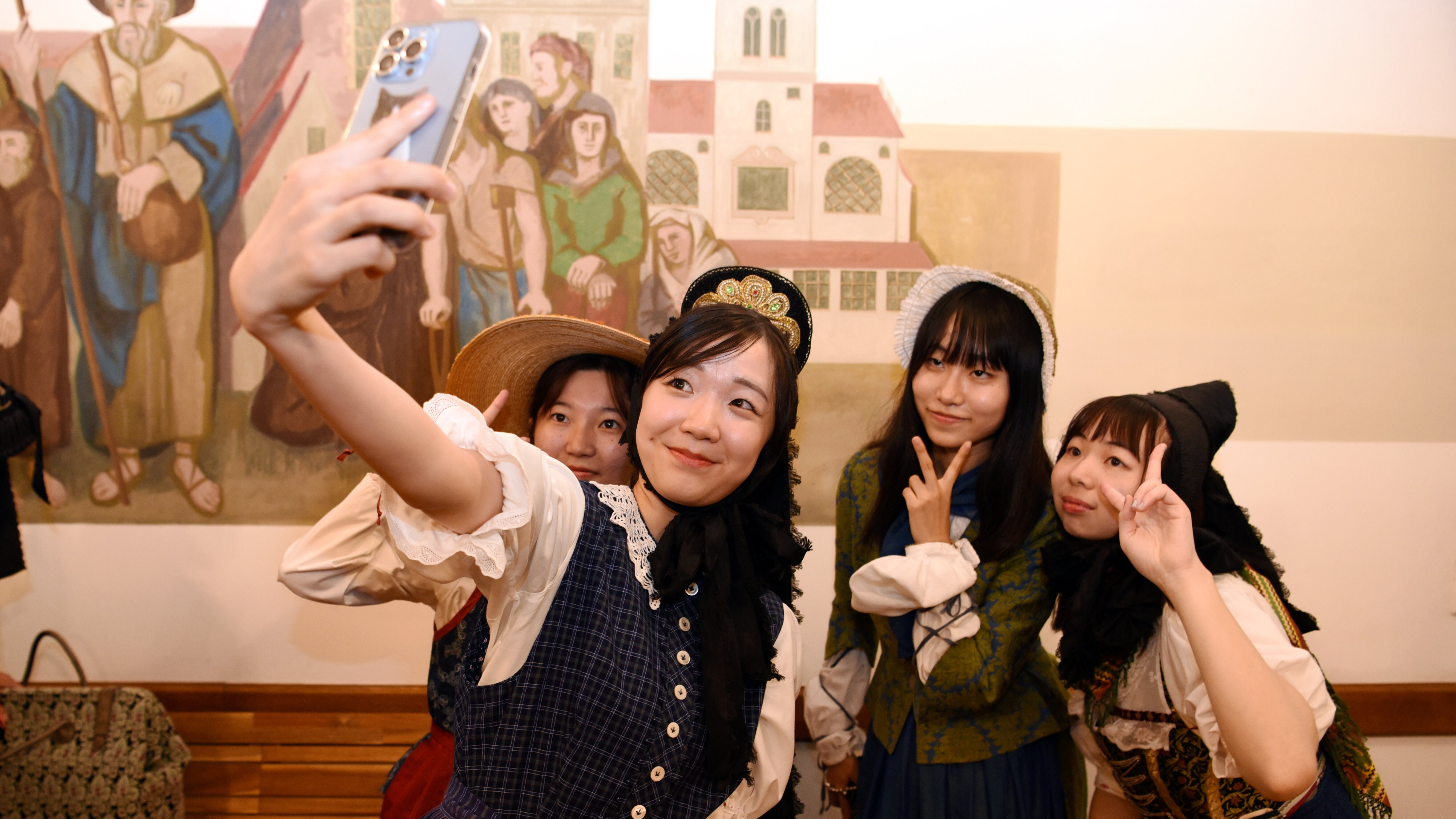 Vier Japanerinnen der Jugenddelegation tragen schwäbische Tracht, die ähnlich aussieht wie ein Dirndl. Alle zeigen ein Peace-zeichen und machen gemeinsam ein Selfie