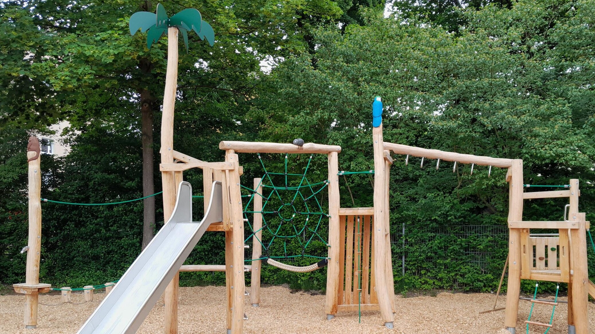 Ein Spielgerät zum Klettern und Balancieren mit einer Rutsche steht auf einem Spielplatz