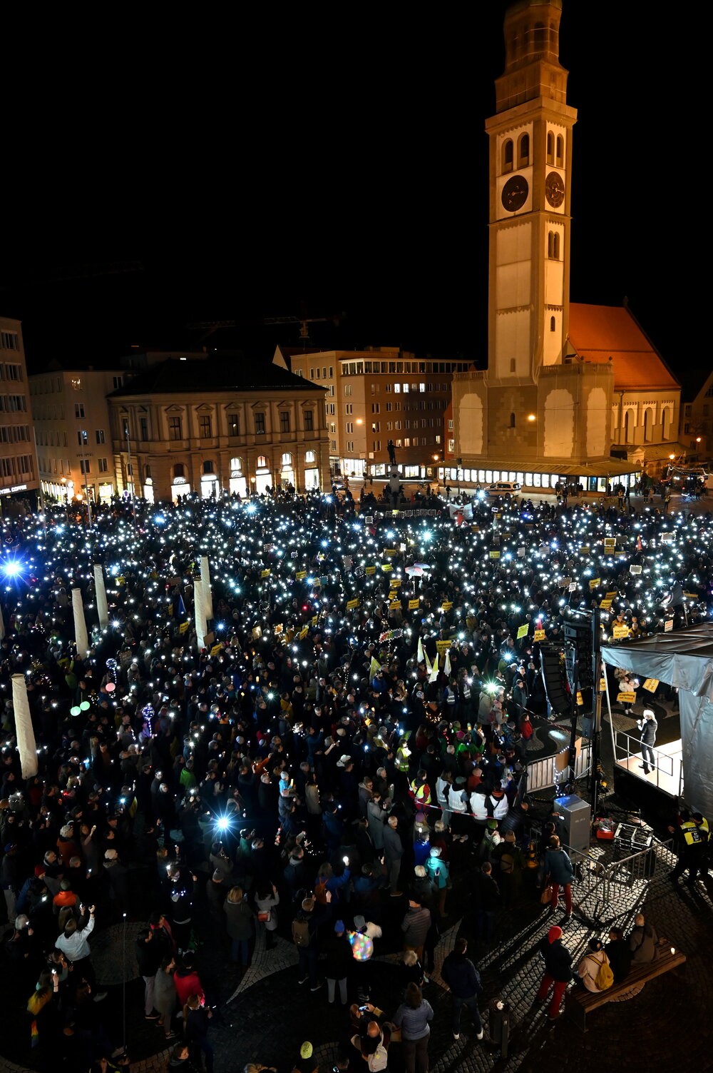 Auf dem Rathausplatz stehen mehrere Tausend Menschen bei Dunkelheit und halten Lichter in die Höhe