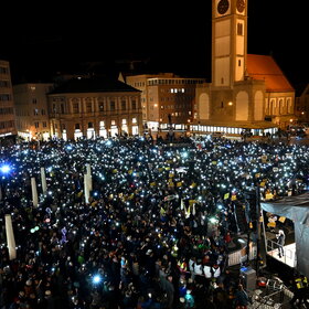 Auf dem Rathausplatz stehen mehrere Tausend Menschen bei Dunkelheit und halten Lichter in die Höhe