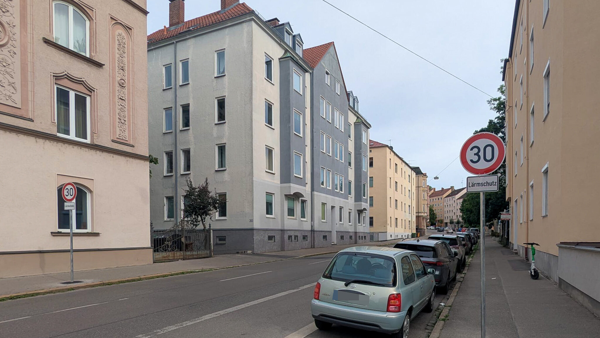 Eine Straße in Augsburg mit einem Verkehrsschild. Es zeigt Tempo 30 mit dem Hinweis "Lärmschutz"