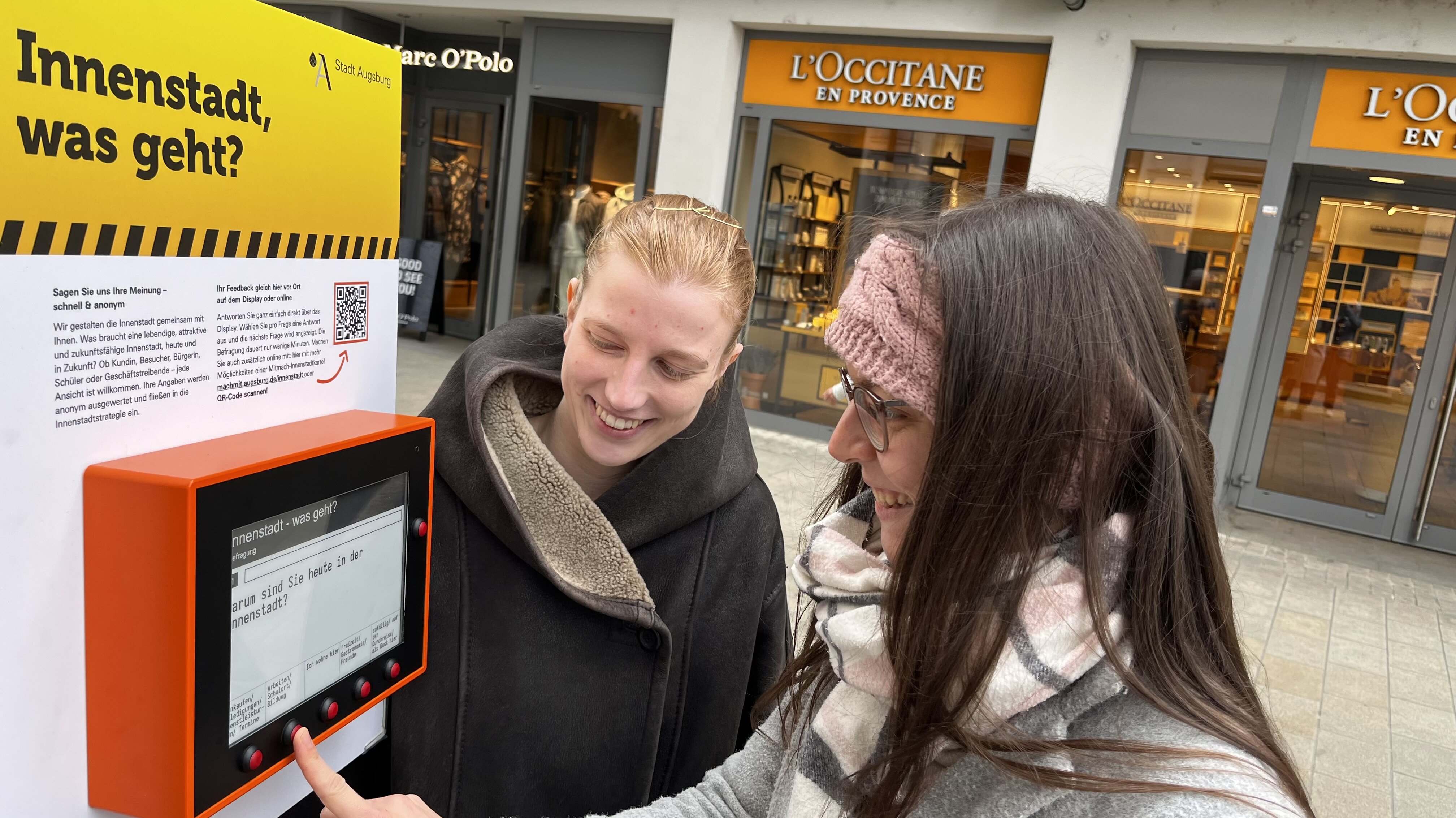 Zwei frauen stehen an einem kleinen Computer in der Fußgängerzone