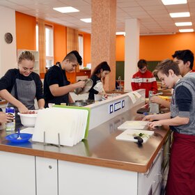 Schülerinnen und Schüler an einem Küchenblock bei der Essensvorbereitung
