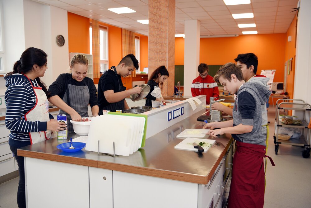 Schülerinnen und Schüler an einem Küchenblock bei der Essensvorbereitung