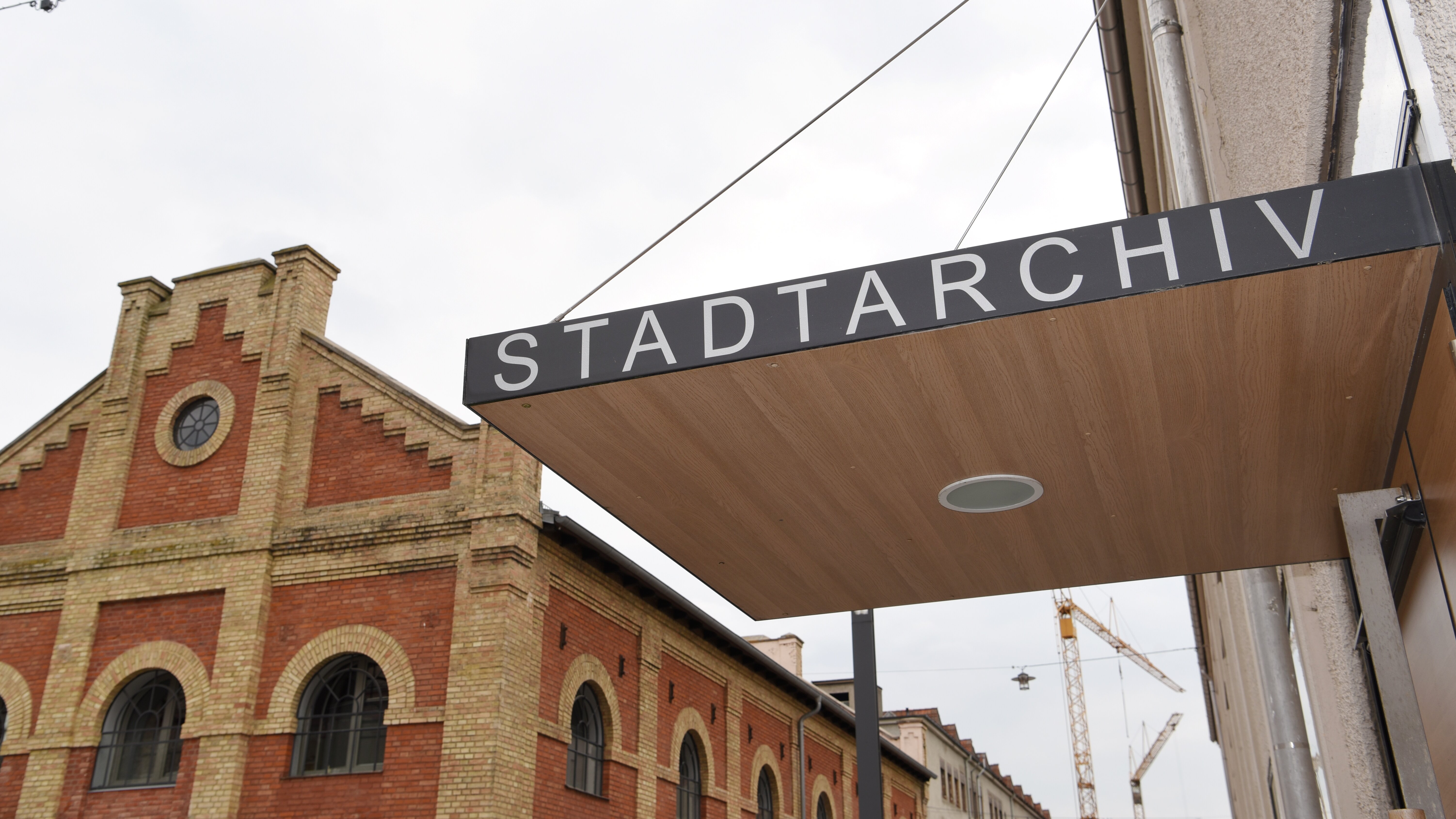 Auf dem Foto ist der Eingangsbereich des Stadtarchivs zu sehen. Im Hintergrund ein rotes Backsteingebäude
