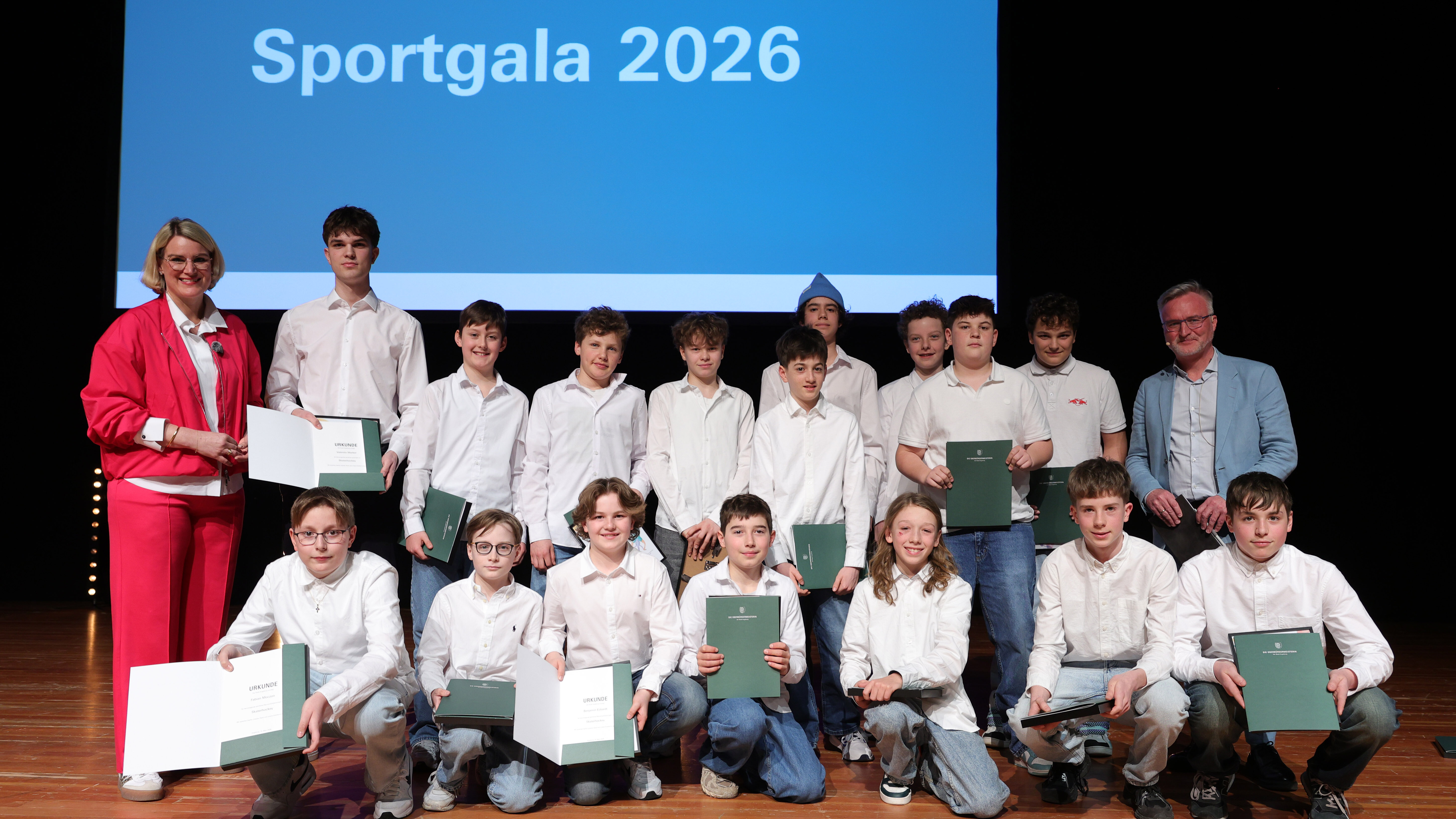 15 Jungs in weißen Hemden halten Urkunden in der Hand. Links und Rechts von Ihnen eine Frau und ein Mann