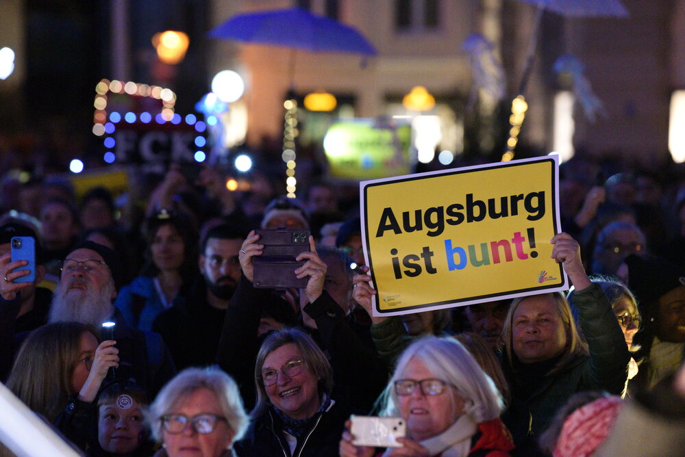 Auf dem Rathausplatz stehen mehrere Tausend Menschen bei Dunkelheit und halten Lichter in die Höhe