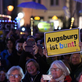 Auf dem Rathausplatz stehen mehrere Tausend Menschen bei Dunkelheit und halten Lichter in die Höhe