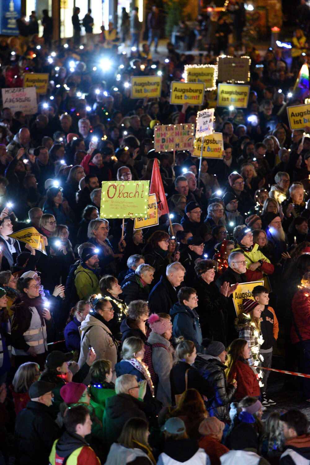 Auf dem Rathausplatz stehen mehrere Tausend Menschen bei Dunkelheit und halten Lichter in die Höhe