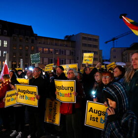 Auf dem Rathausplatz stehen mehrere Tausend Menschen bei Dunkelheit und halten Lichter in die Höhe