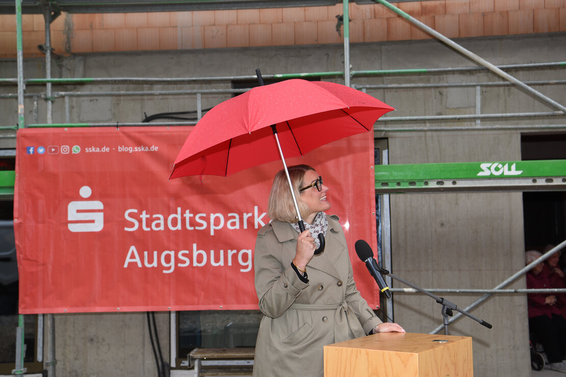 OB Eva Weber am Rednerpult, sie hält einen Schirm über sich