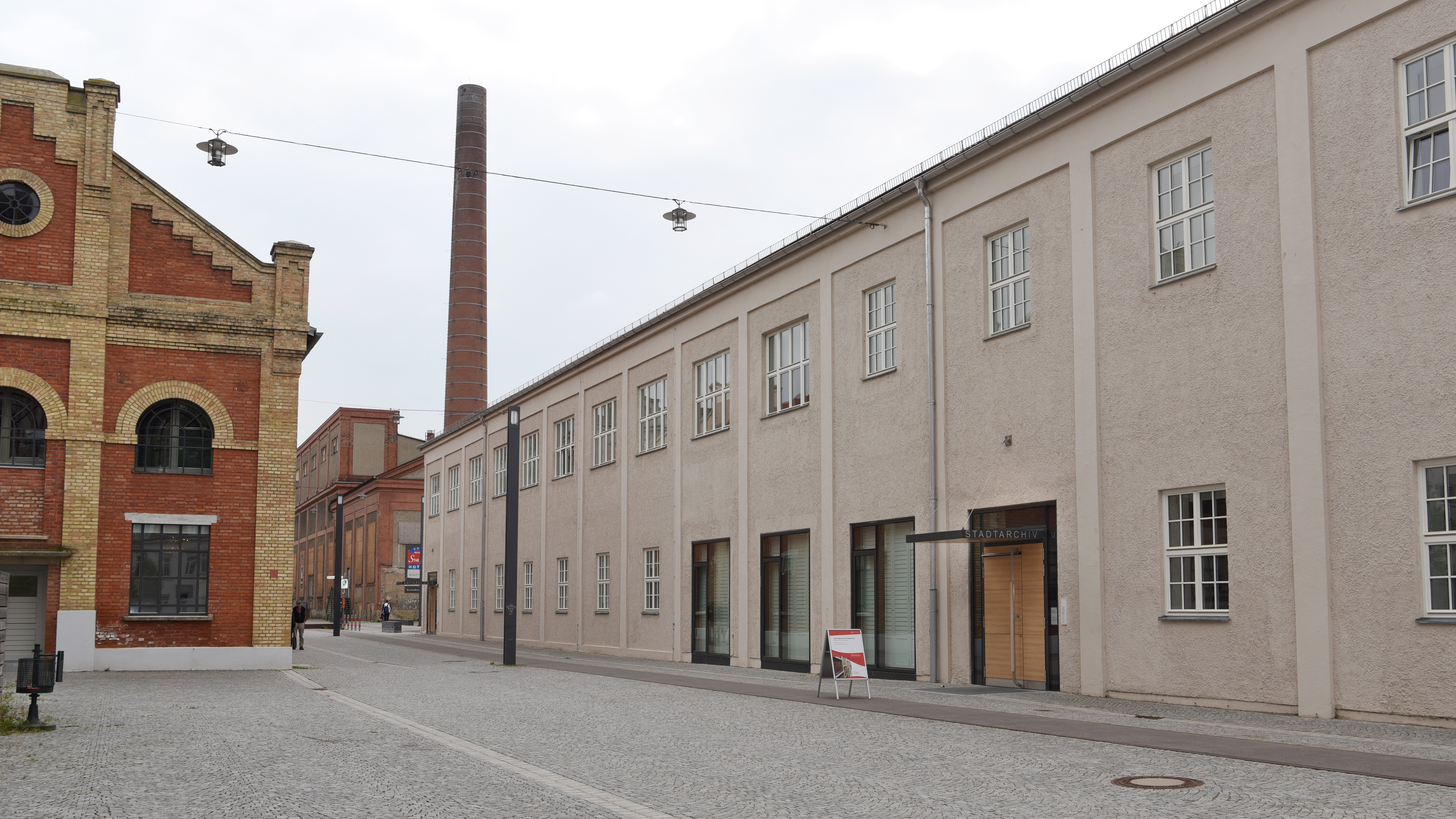 Das Foto zeigt ein längliches graues Gebäude. Über dem Eingang steht Stadtarchiv