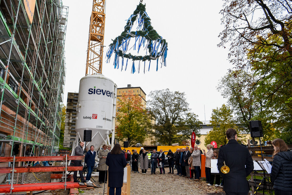 schwebende Richtkrone vor Rohbau mit Gerüst und Betonsilo