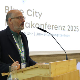 Umweltreferent der Stadt Augsburg, Reiner Erben, steht an einem Rednerpult und spricht.