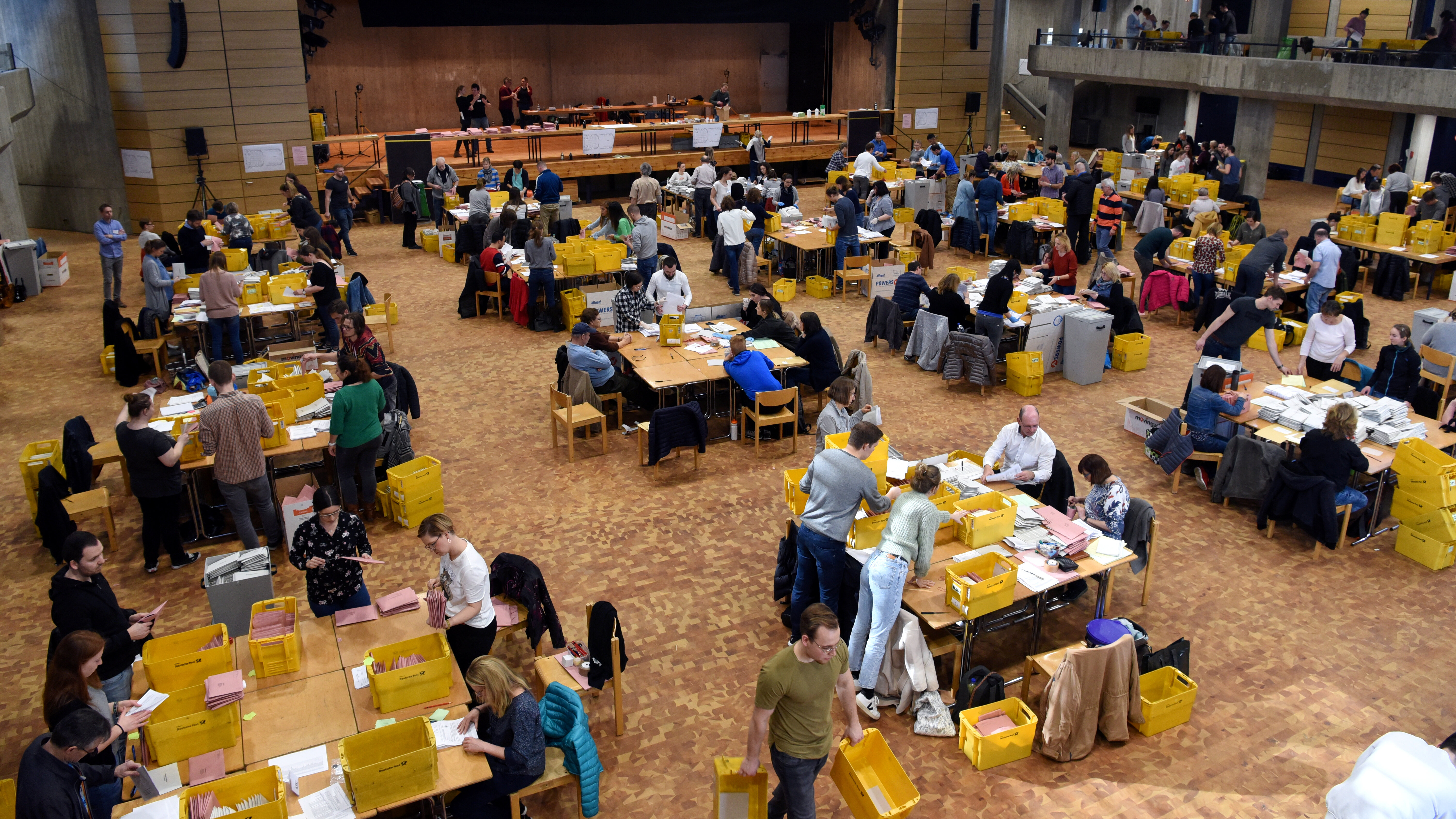 Viele Leute an mehr als 10 großen Tischen zählen Wahlzettel