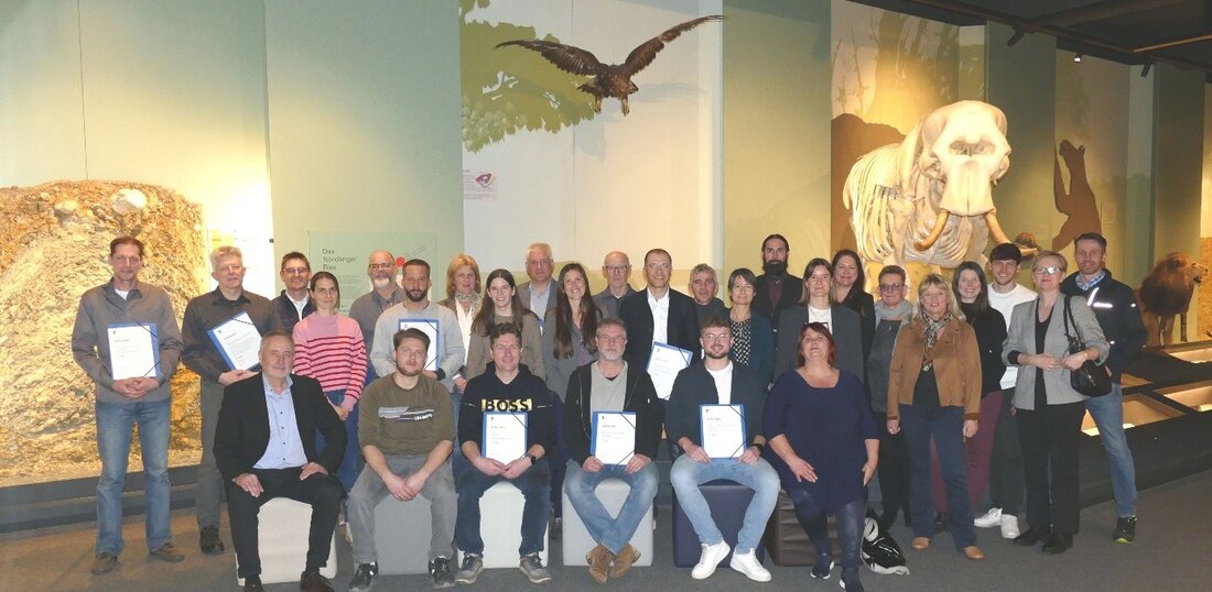Etwa 25 Leute stehen und sitzen im Naturmuseum. Einige halten Urkunden in der Hand.