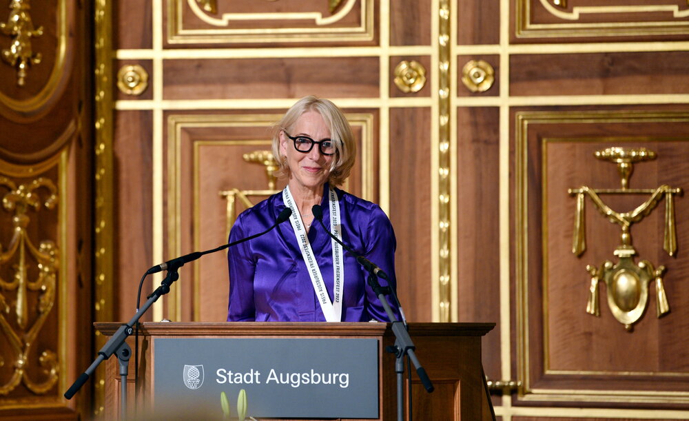 Eine Frau steht hinter einem Pult und hält eine Rede.