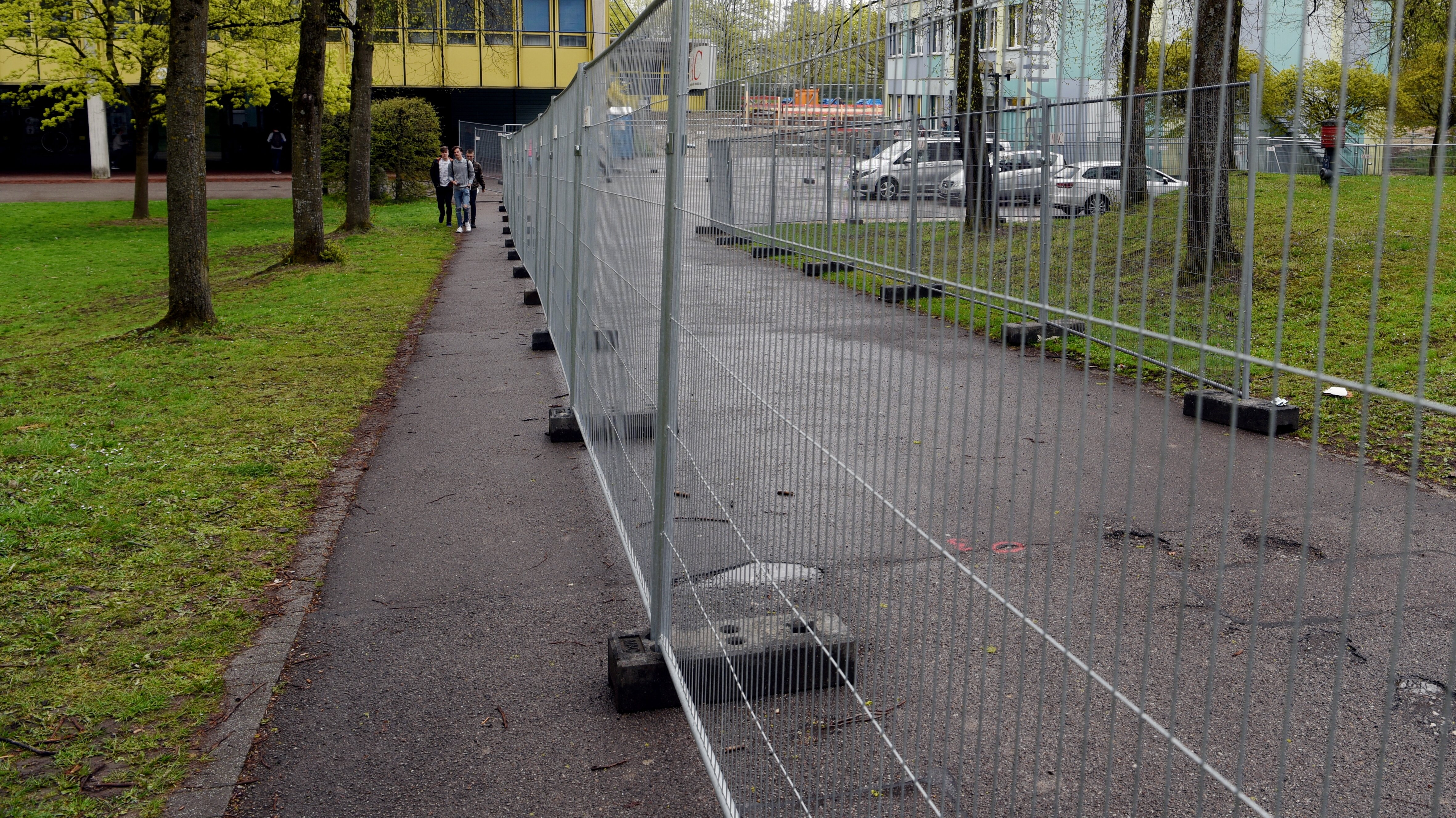 Ein Bauzaun vor einem Schulgebäude