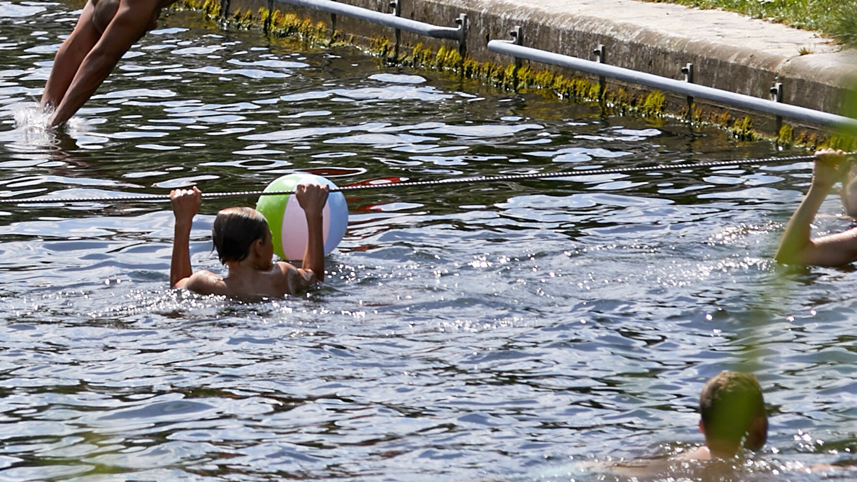 ein Kind im Wasser hält sich an einem gespannten Seil fest