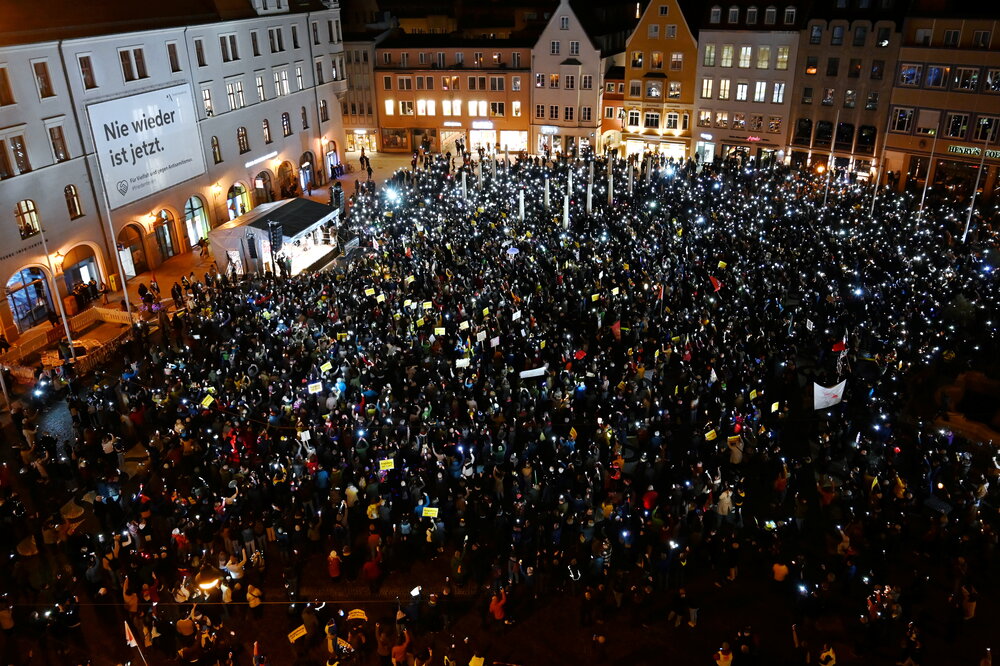 Auf dem Rathausplatz stehen mehrere Tausend Menschen bei Dunkelheit und halten Lichter in die Höhe