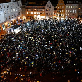 Auf dem Rathausplatz stehen mehrere Tausend Menschen bei Dunkelheit und halten Lichter in die Höhe