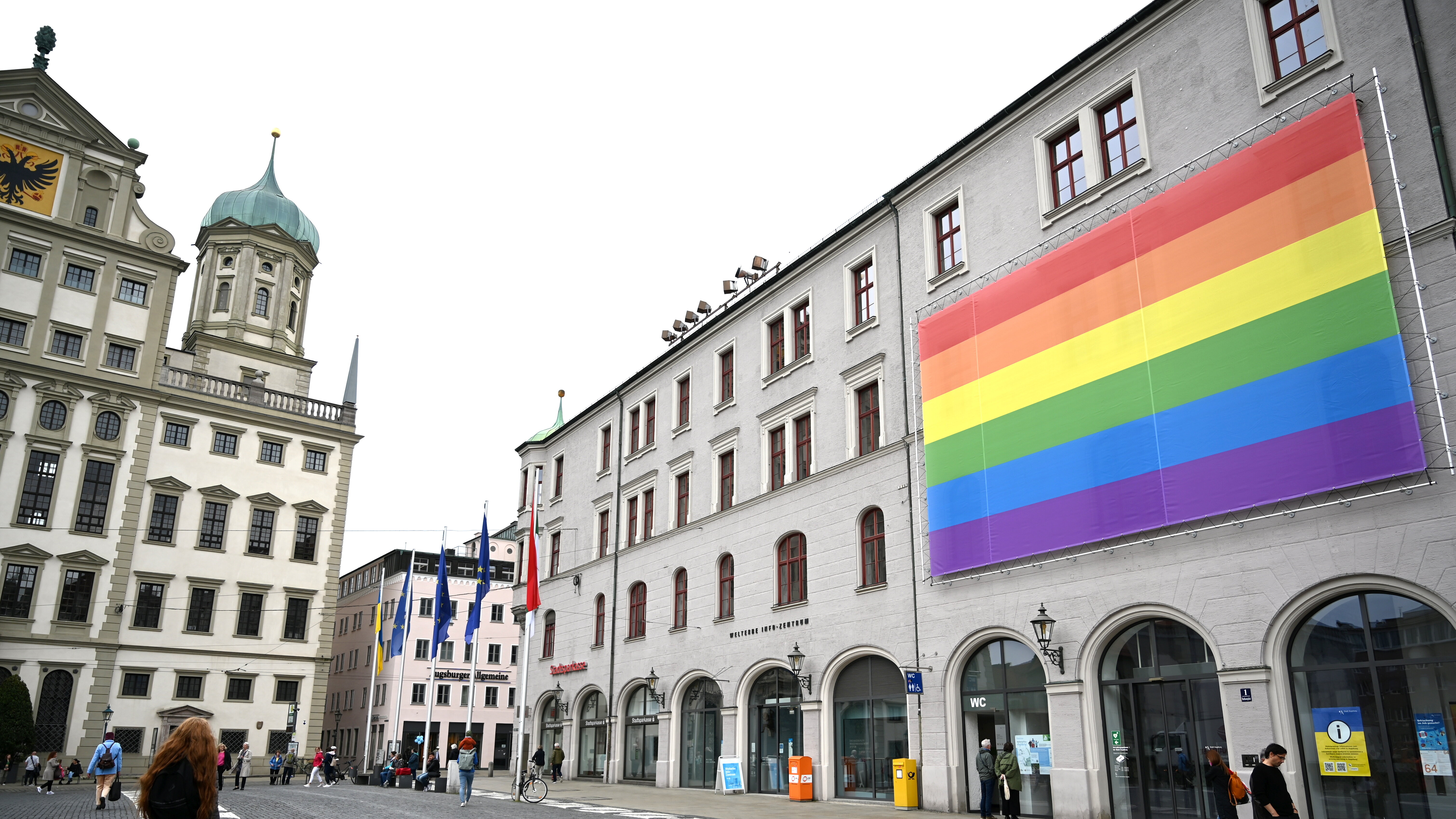Das Foto zeigt den Rathausplatz. Am Gebäude der Sparkasse hängt eine große Regenbogenfahne