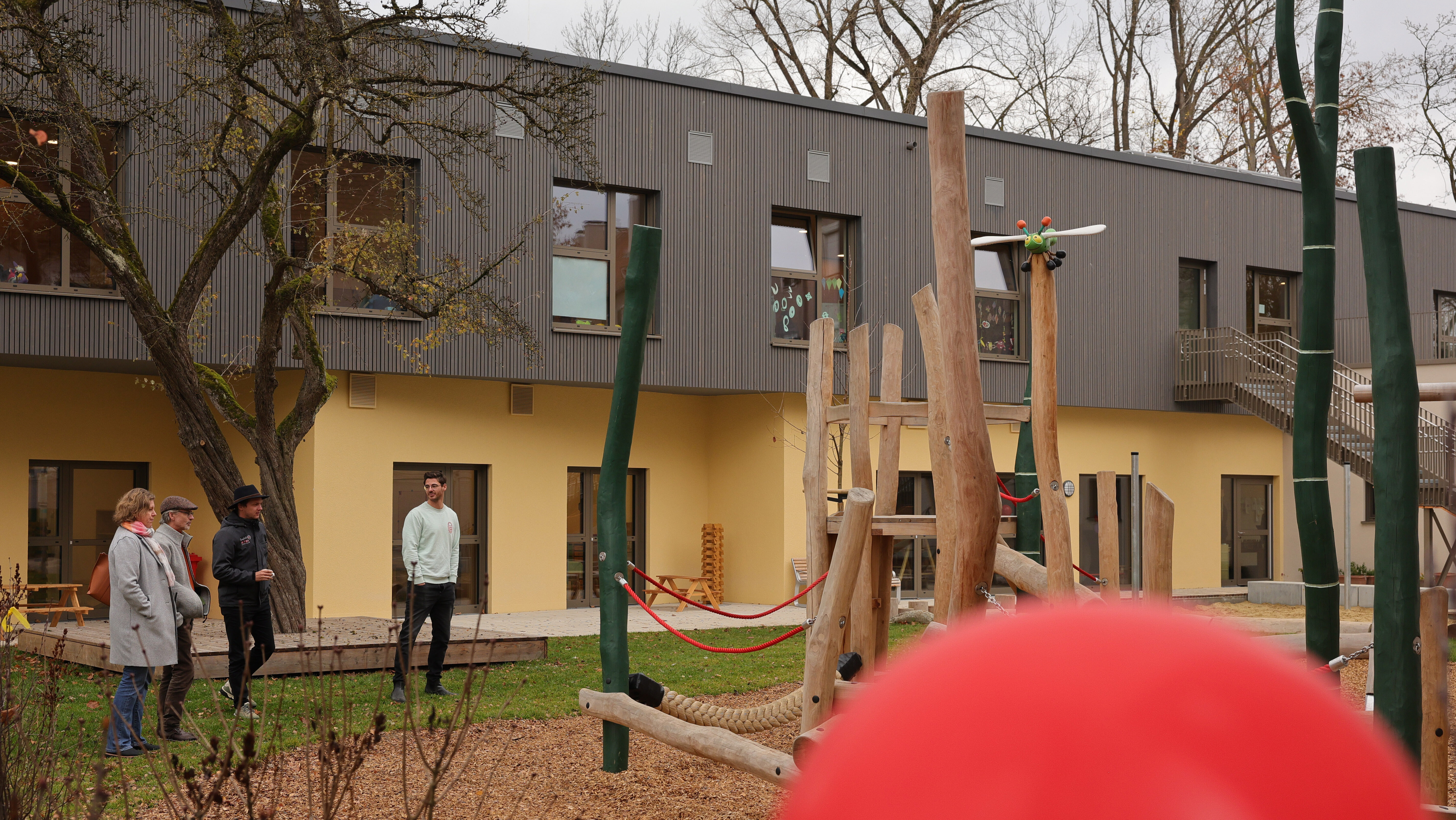 Ein zweistöckiges Gebäude. Im Garten stehen Spielgeräte