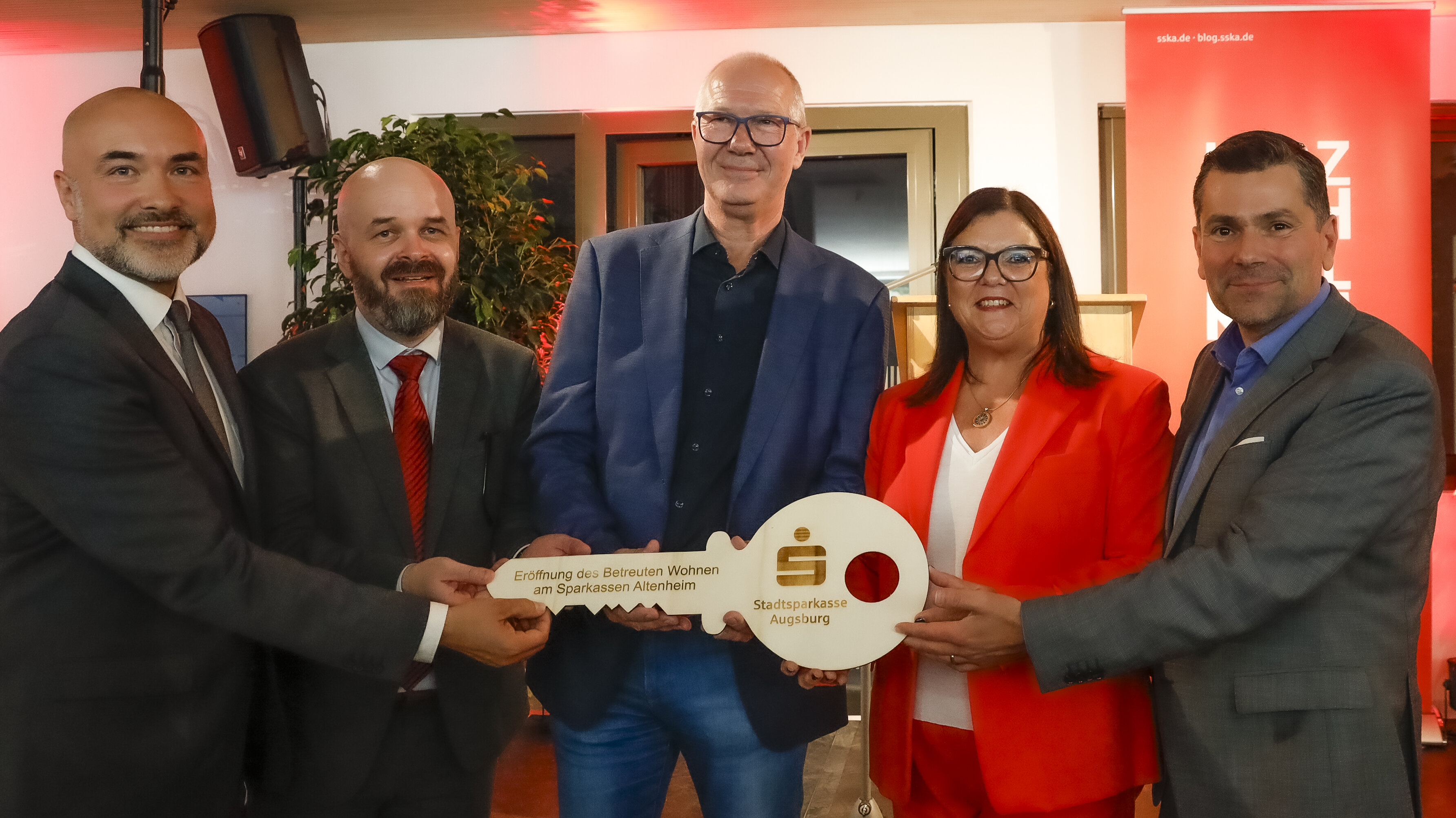 Fünf Personen halten einen riesigen Schlüssel