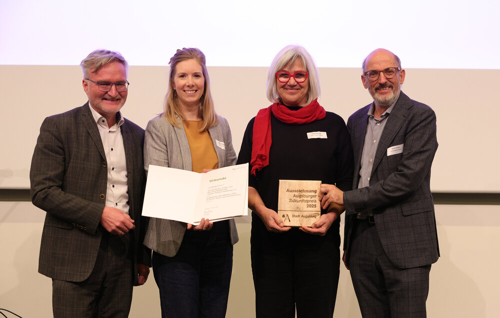 4 Personen halten eine Urkunde in die Kamera