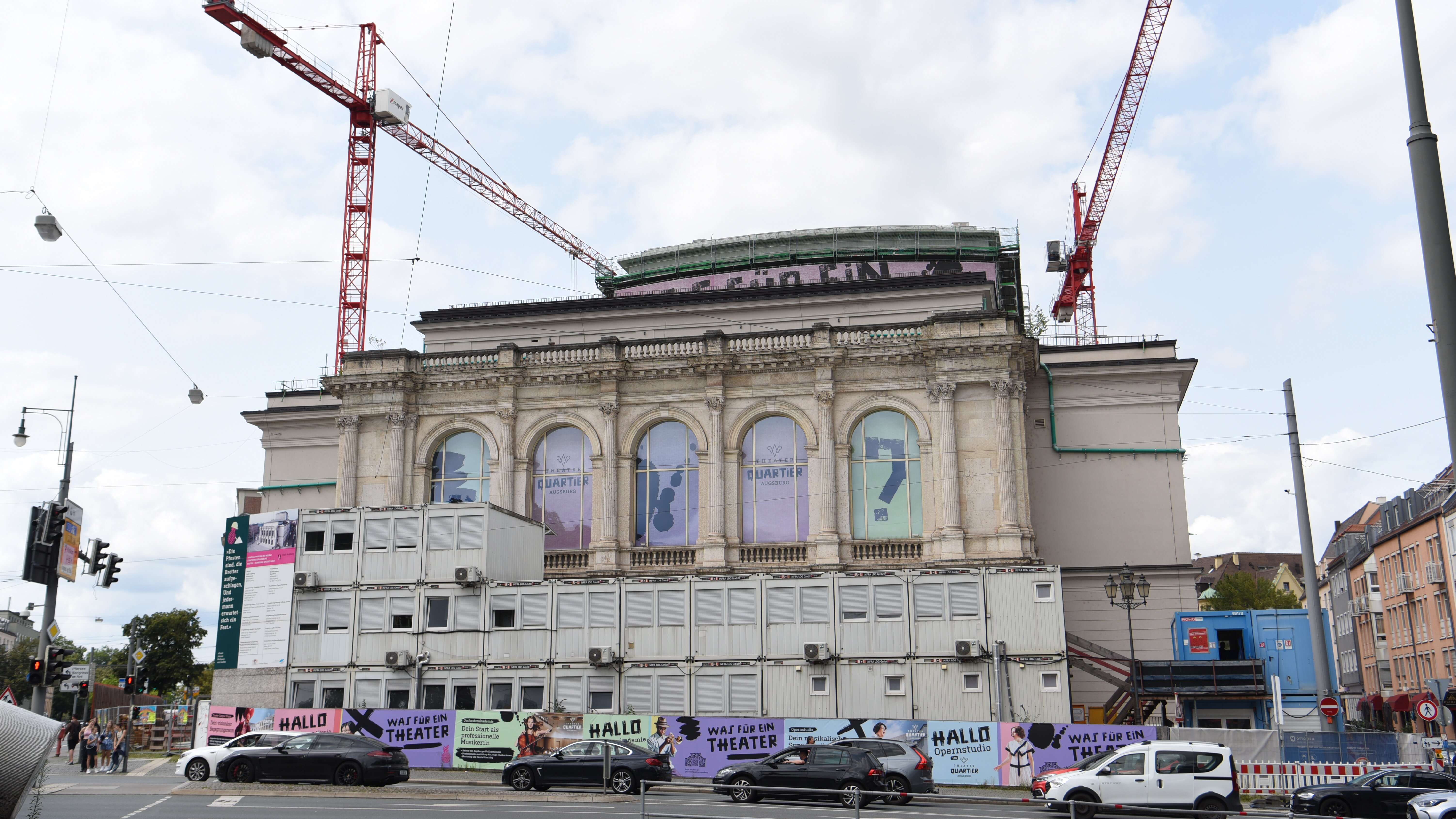 Neoklassizistischer Theaterbau, der von aufeinander gestapelten Großcontainern halb verdeckt ist