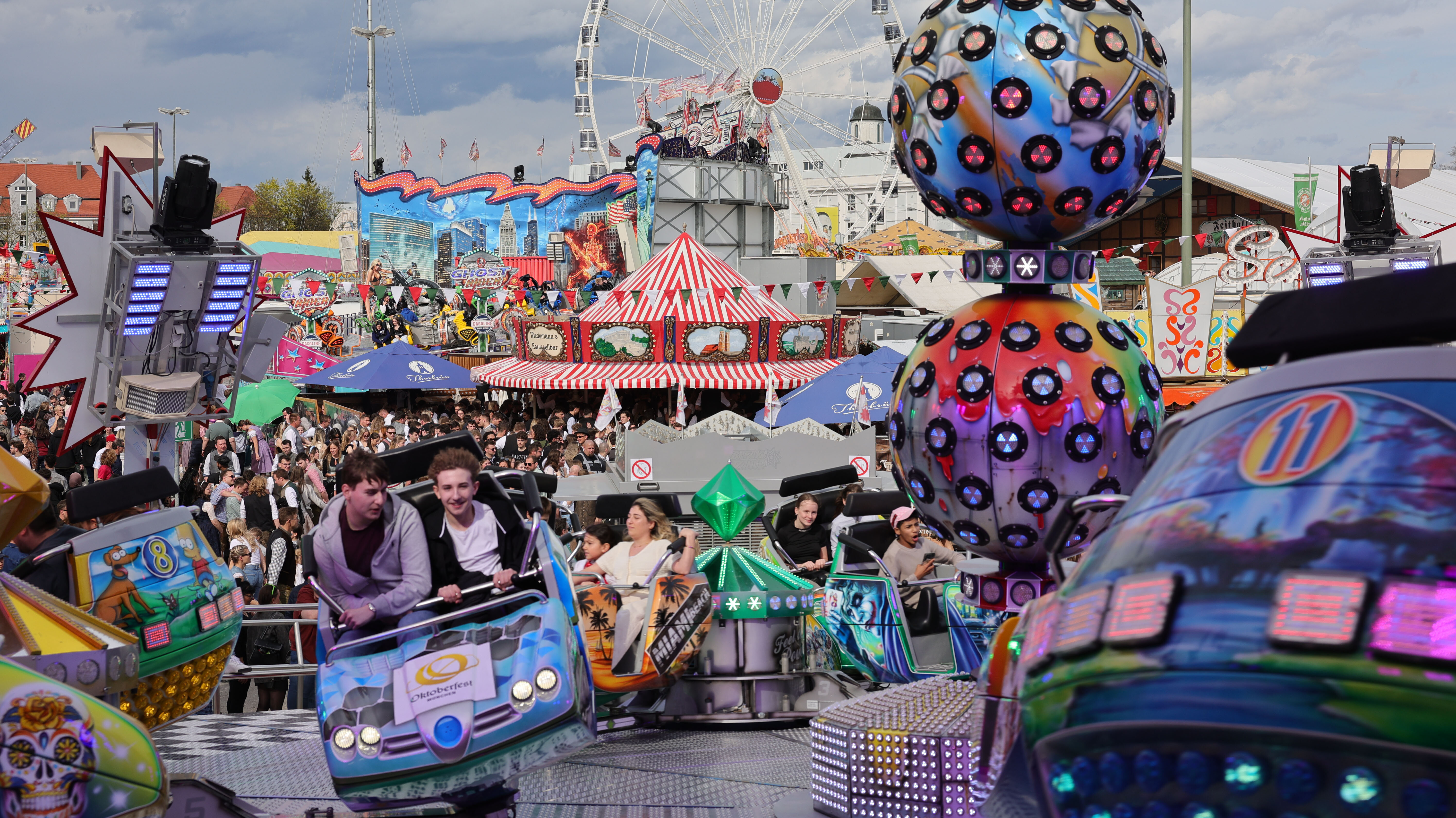Reges Treiben beim Familientag auf dem Augsburger Plärrer. Zu sehen ist ein buntes Fahrgeschäft mit sich drehenden Kabinen. Im Hintergrund das Riesenrad . 