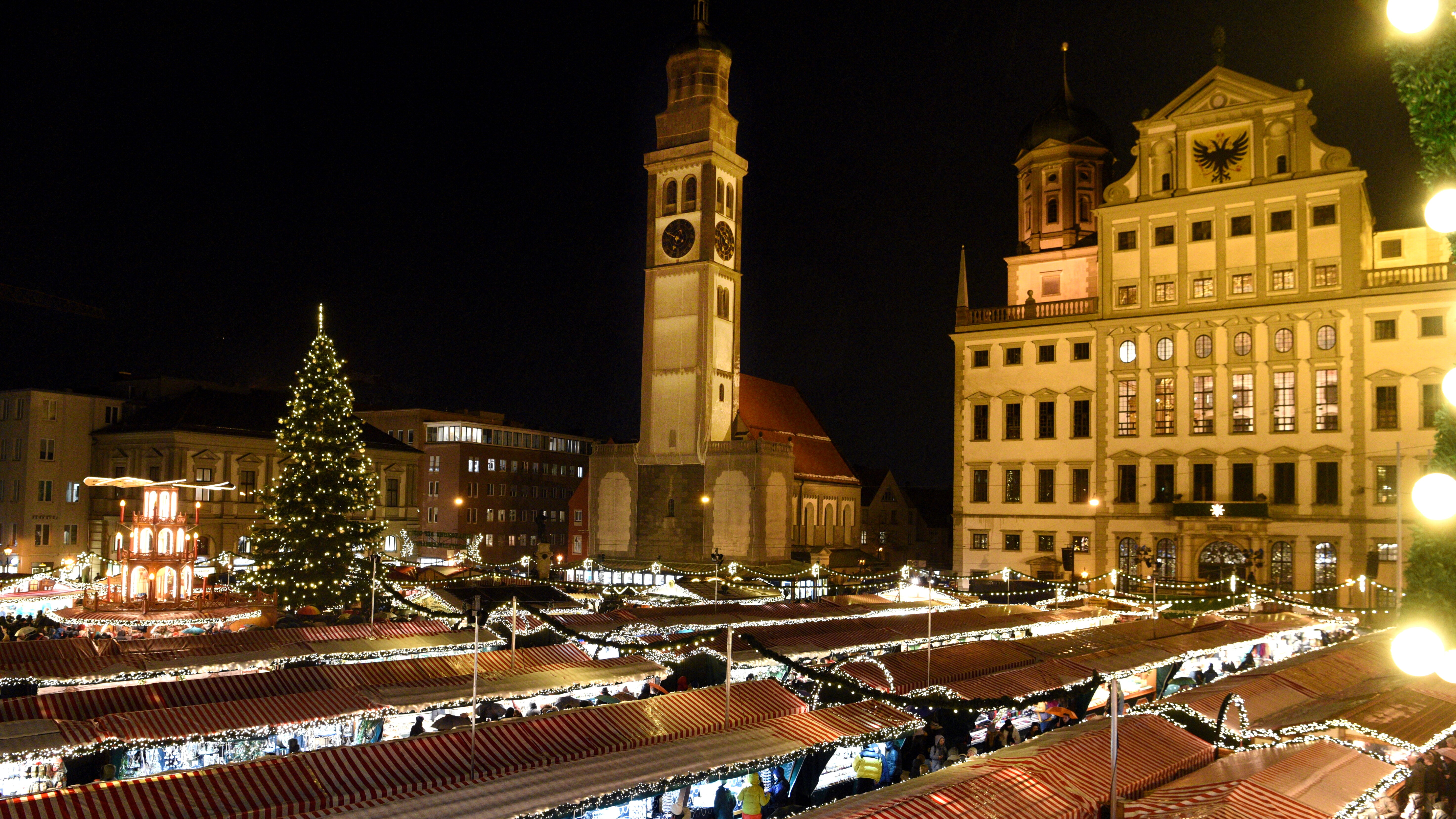 Blick über den Christkindlesmarkt bei Nacht. Im Hintergrund stehen Rathaus und Perlachturm
