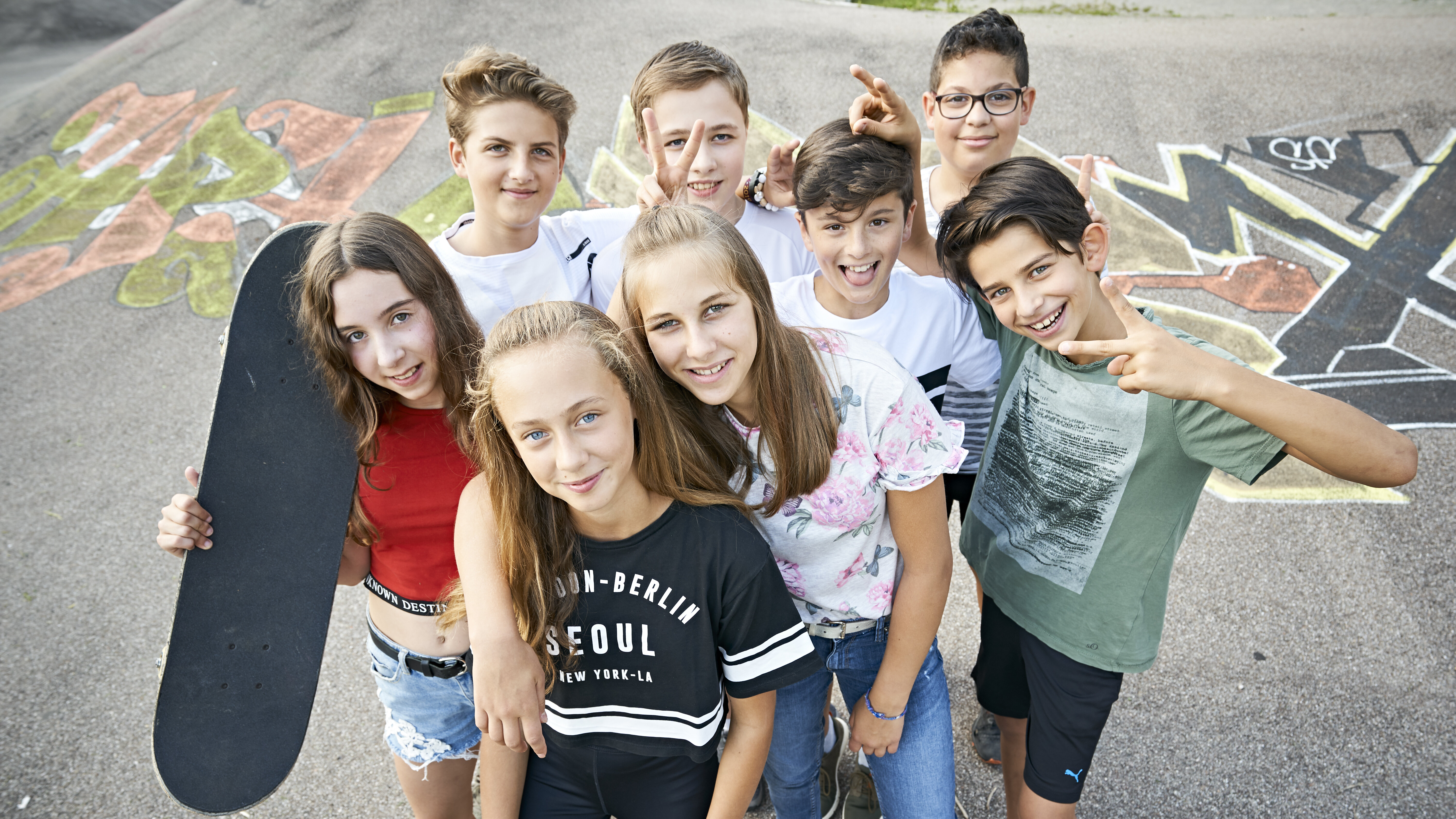 Acht Jugendliche stehen mit Skateboards auf einer Skater-Anlage