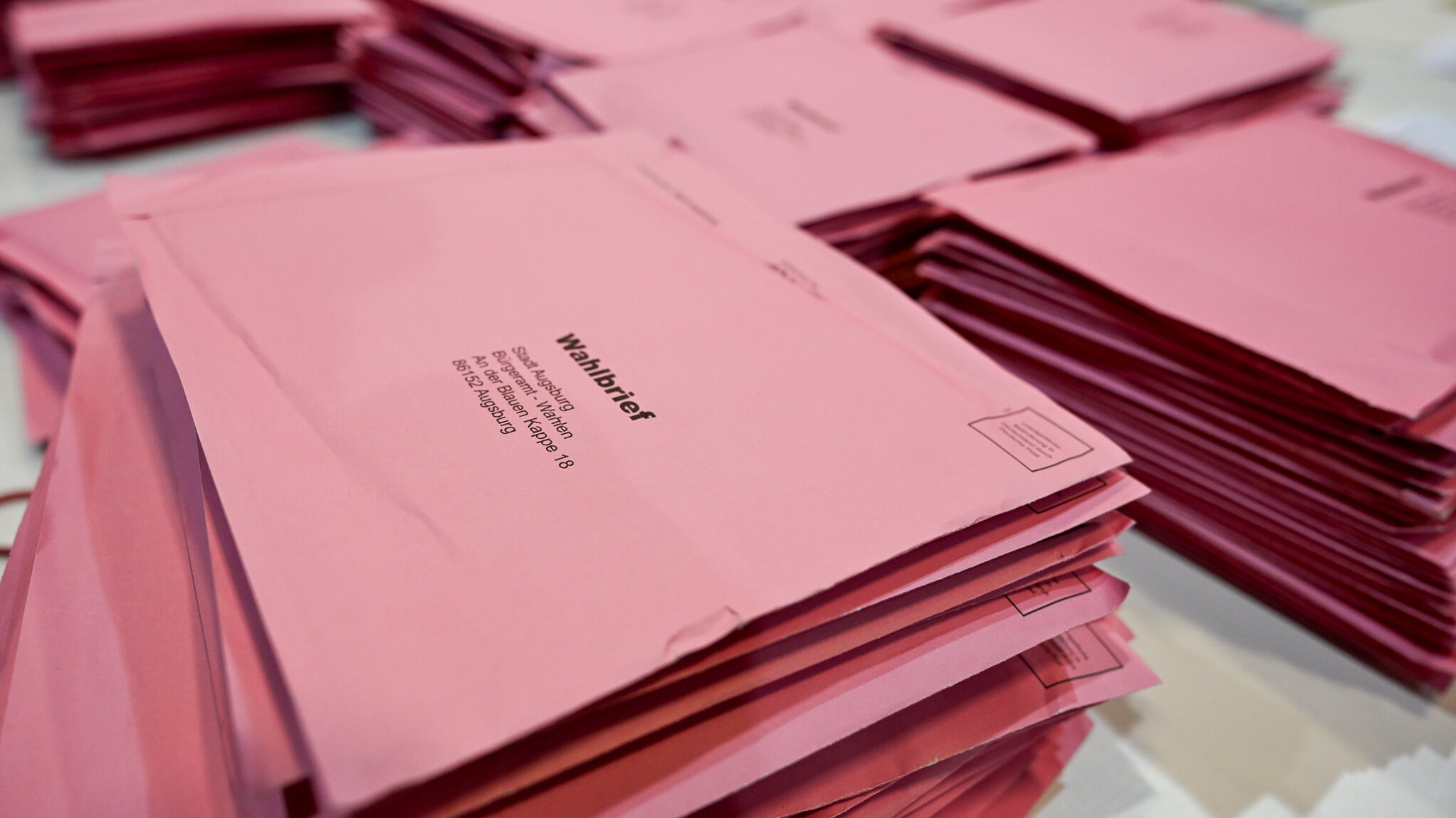 Das Foto zeigt mehrere Stapel der rosa Wahlumschläge, die auf einem Tisch liegen