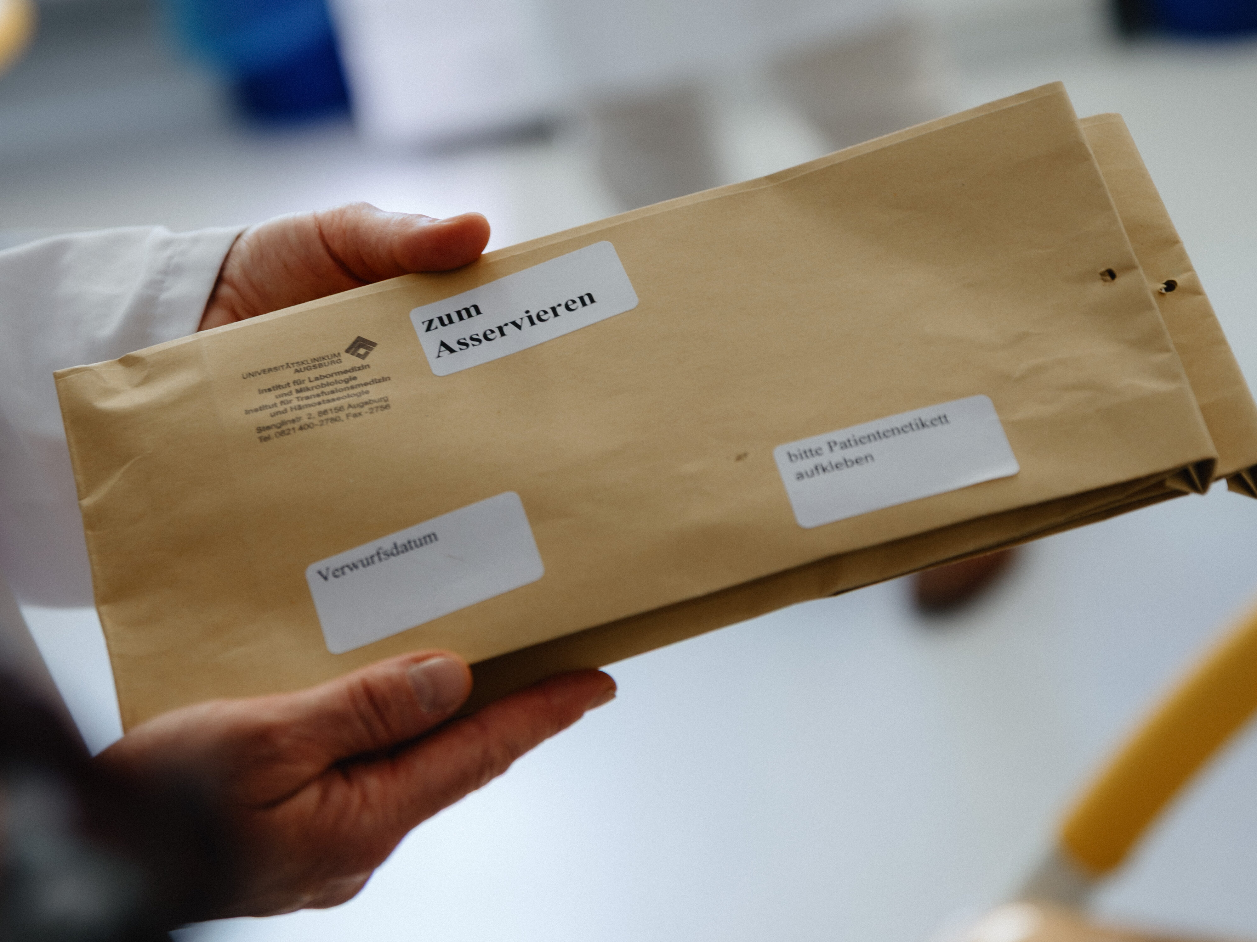 zwei Hände halten einen Umschlag, auf dem "Zu asservieren" steht
