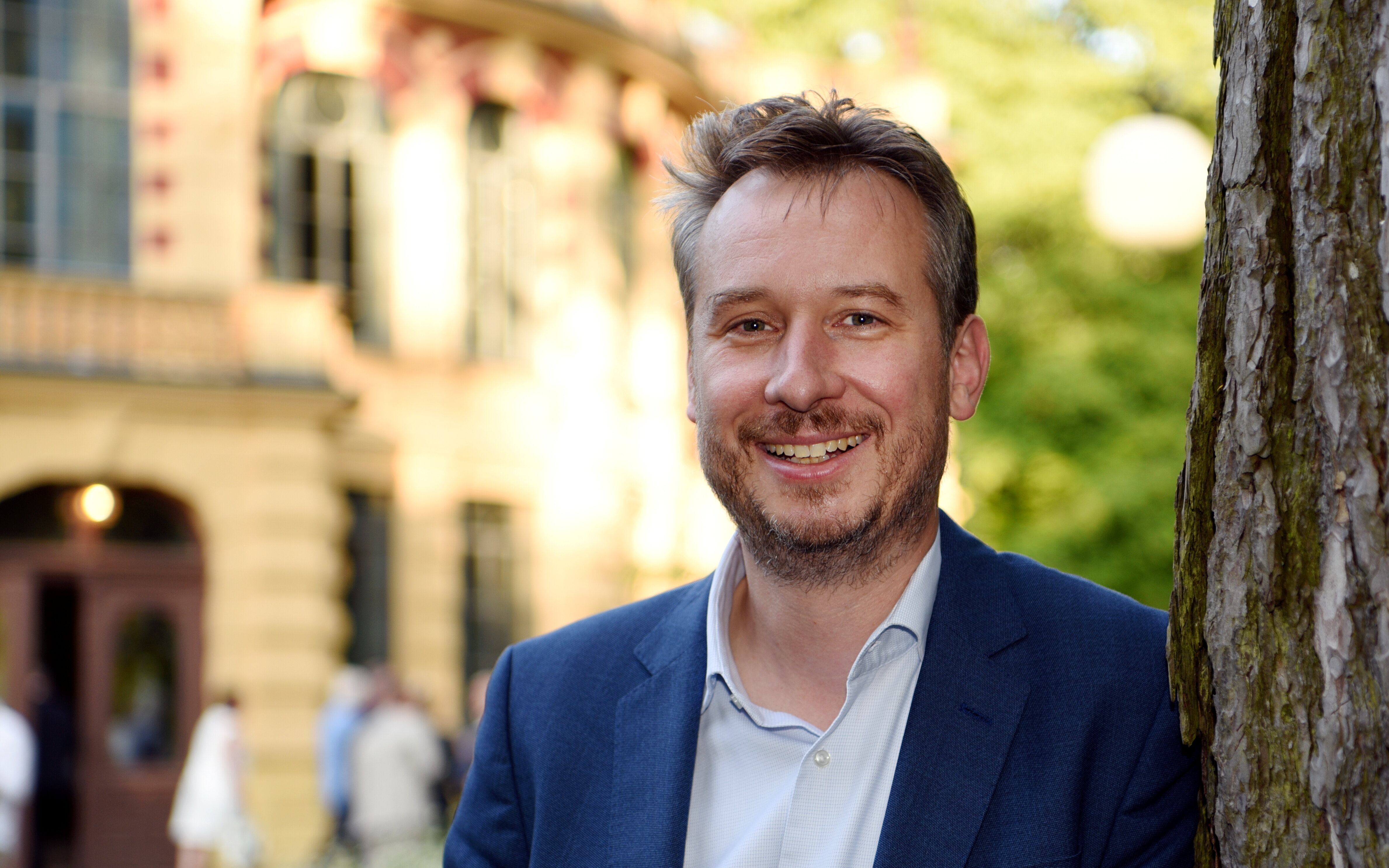 Steffen Kercher steht neben einem Baum. Im Hintergrund ist das Kurhaus Göggingen zu sehen