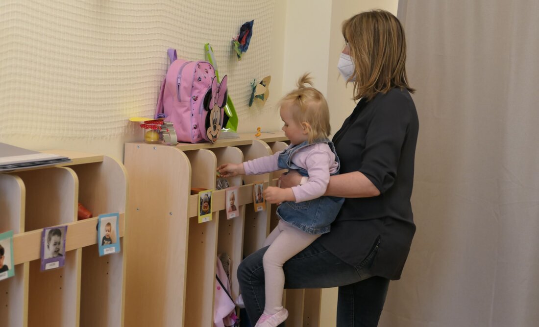 Tagespflegeperson mit Kind in der Garderobe Tagespflegeperson mit Kind in der Garderobe