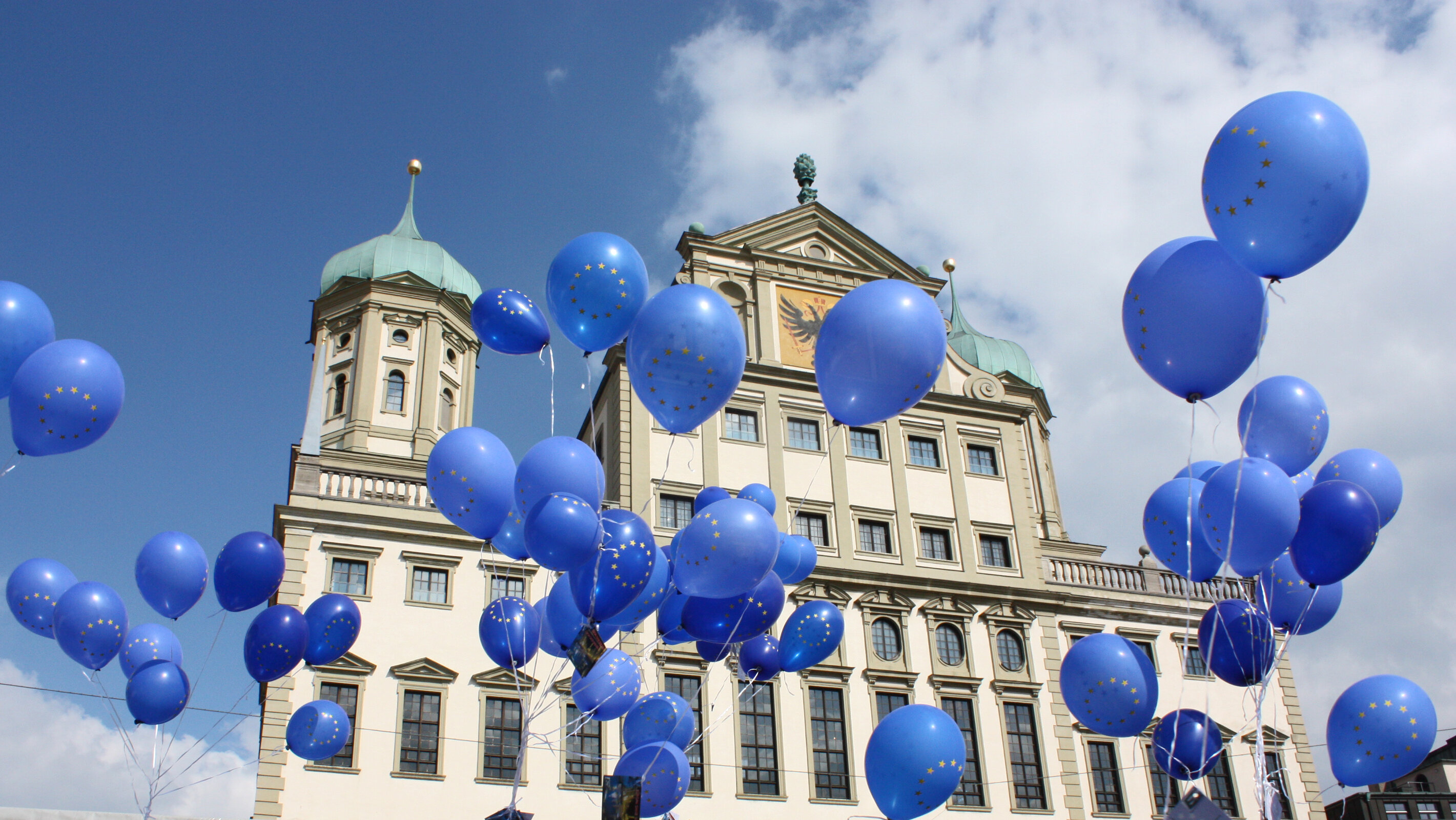 Vor dem Augsburger Rathaus steigen blaue Luftballons mit dem Zeichen der Europäischen Union in die Luft