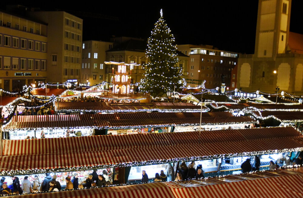 Blick über die hell erelcuhtete Budenstadt auf den großen Christbaum für alle