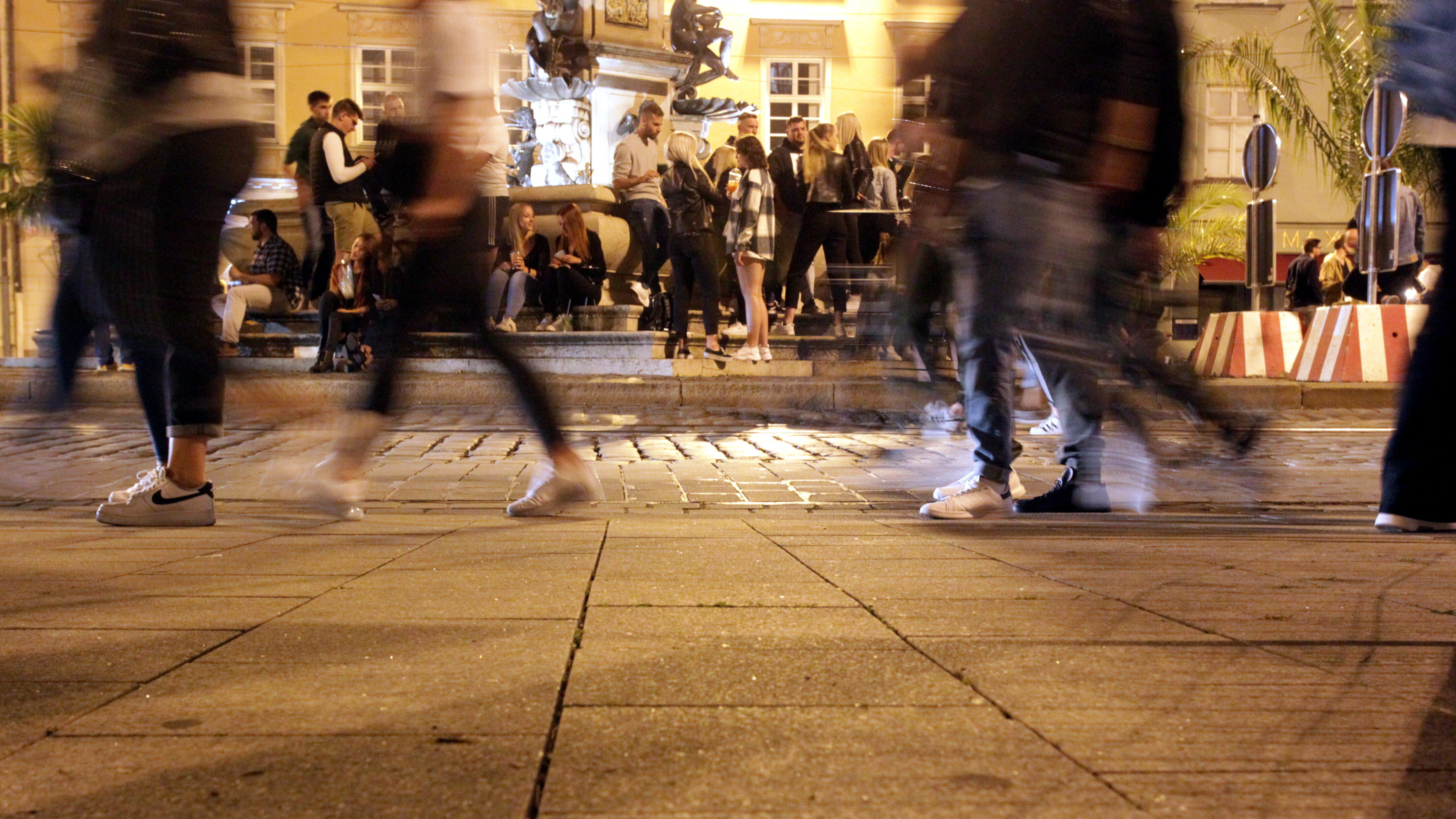 Viele junge Leute sitzen an einem Sommerabend am Herkulesbrunnen.