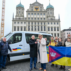Das Bild zeigt die Delgation aus Perwomajsk und Vertreterinnne und Vertreter der Stadt Augsburg bei der Schlüsselübergabe für den Transporter.