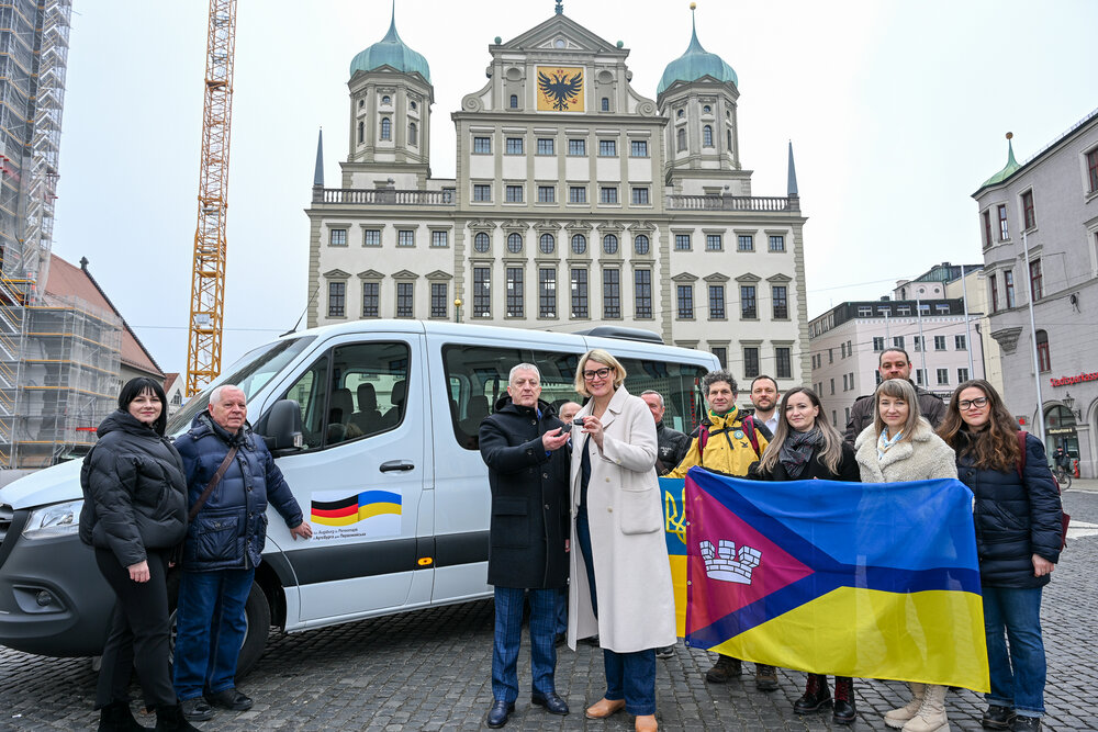 Das Bild zeigt die Delgation aus Perwomajsk und Vertreterinnne und Vertreter der Stadt Augsburg bei der Schlüsselübergabe für den Transporter.