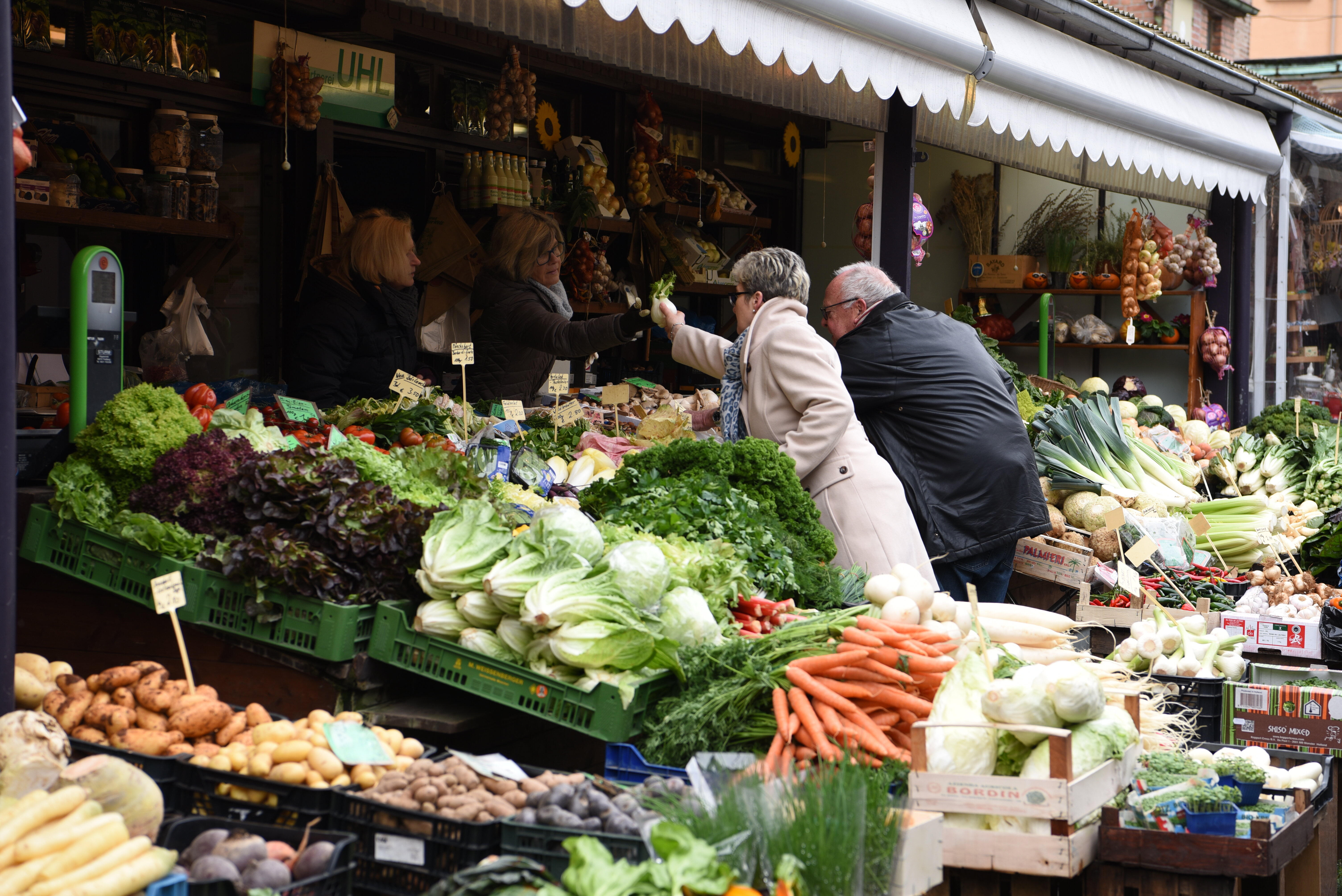 Ein Stand mit vielen Kisten voller Salat und Gemüse auf dem Stadtmarkt.