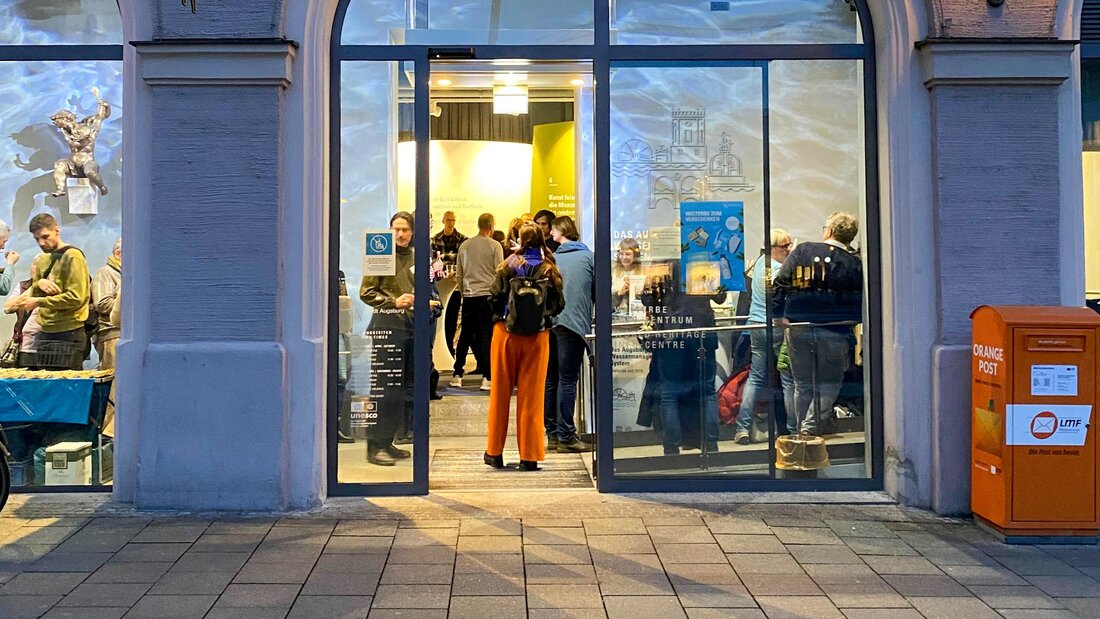 Der barrierefreie Eingang des Welterbe-Infozentrums. Im Innern sind mehrere Personen zu sehen, die an einer Veranstaltung teilnehmen.