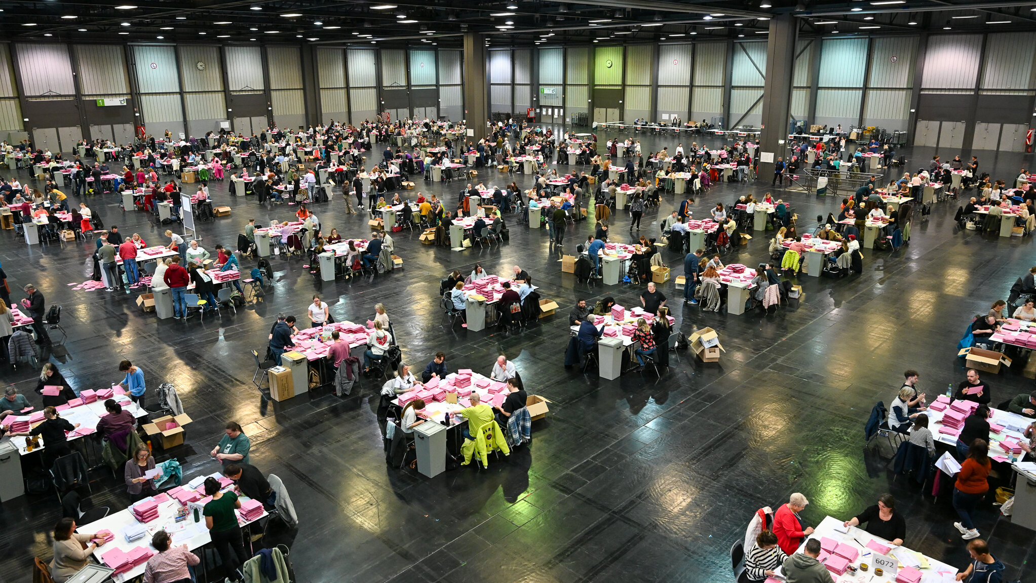 Viele Menschen an vielen Tischen in einer großen Halle. 