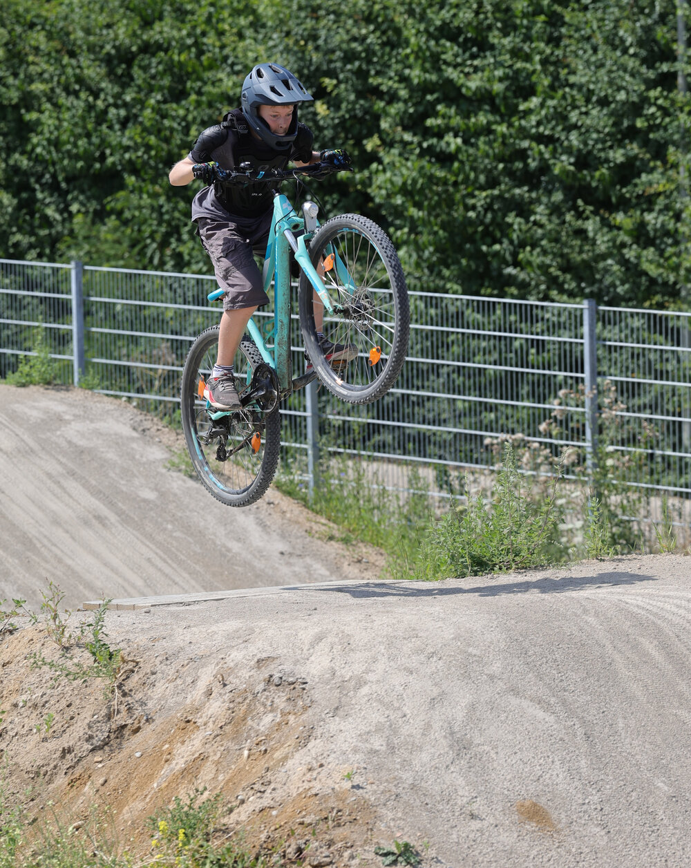 Ein Junge springt mit seinem Fahrrad über ein Hindernis